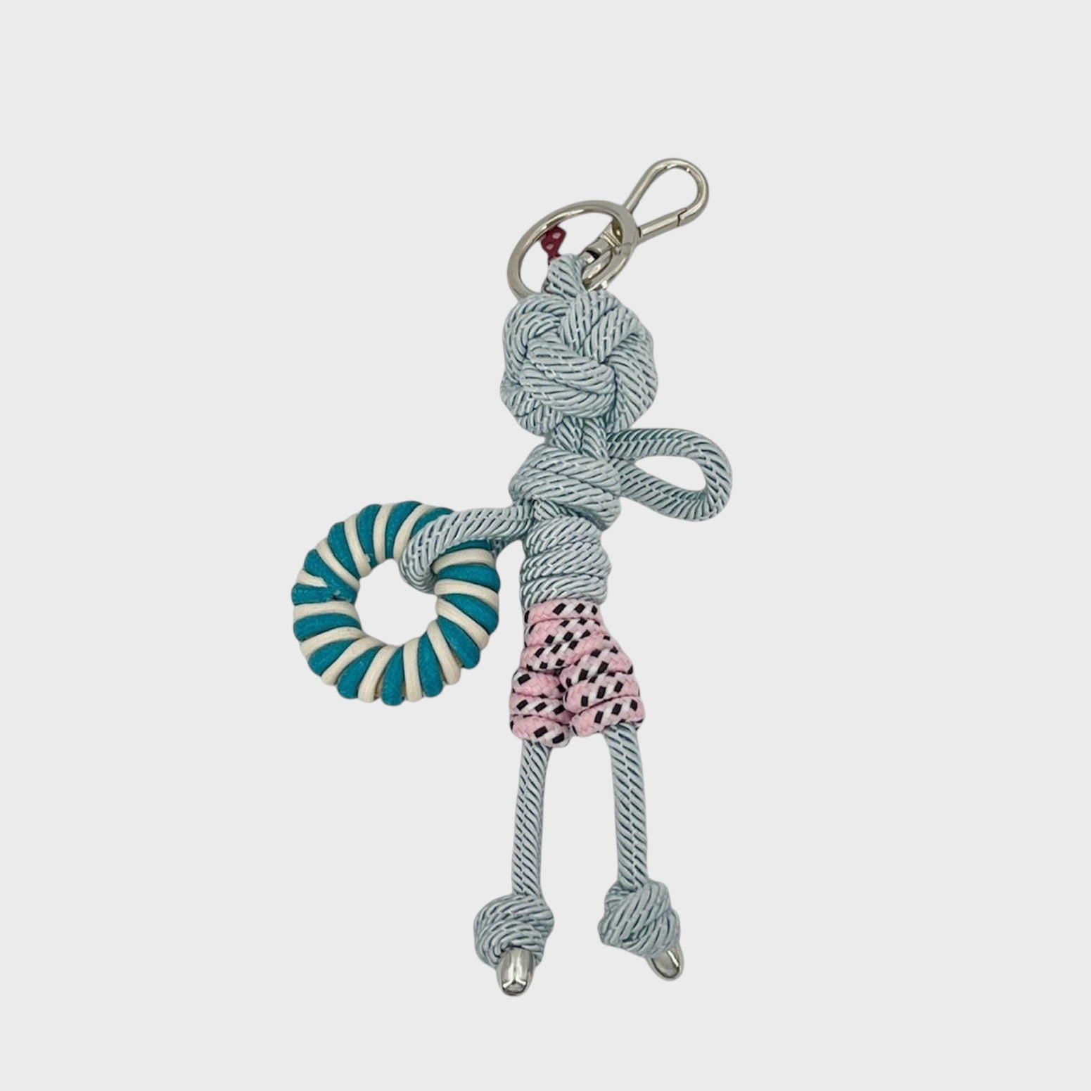 Handmade blue macramé bag charm featuring a male character, meant to be at the beach, wearing striped pink and white swimming shorts and holding a pool float. He is attached to a silver clasp.