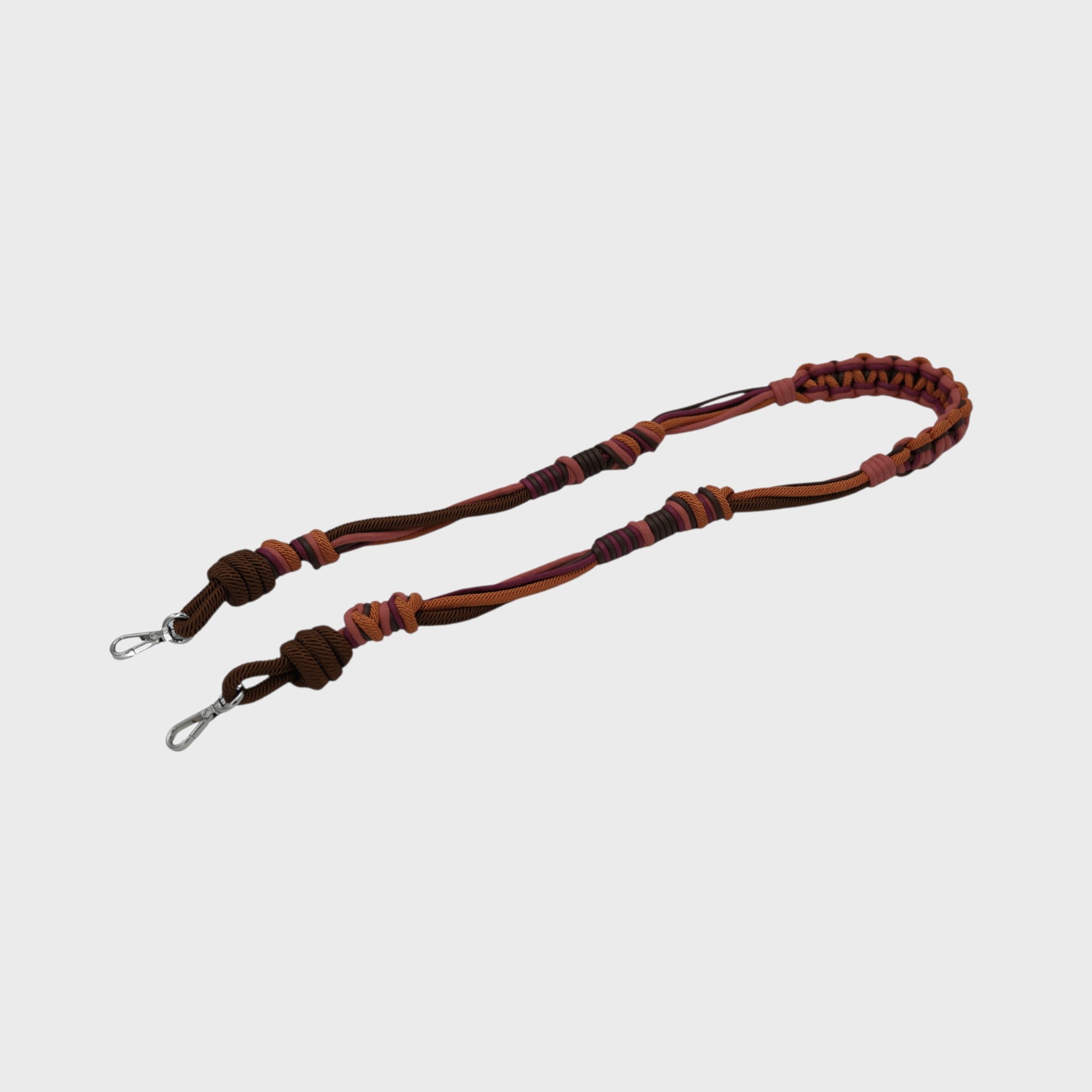 Multicolored braided macramé bag strap in orange, dark brown, and red, shown on a light gray background.