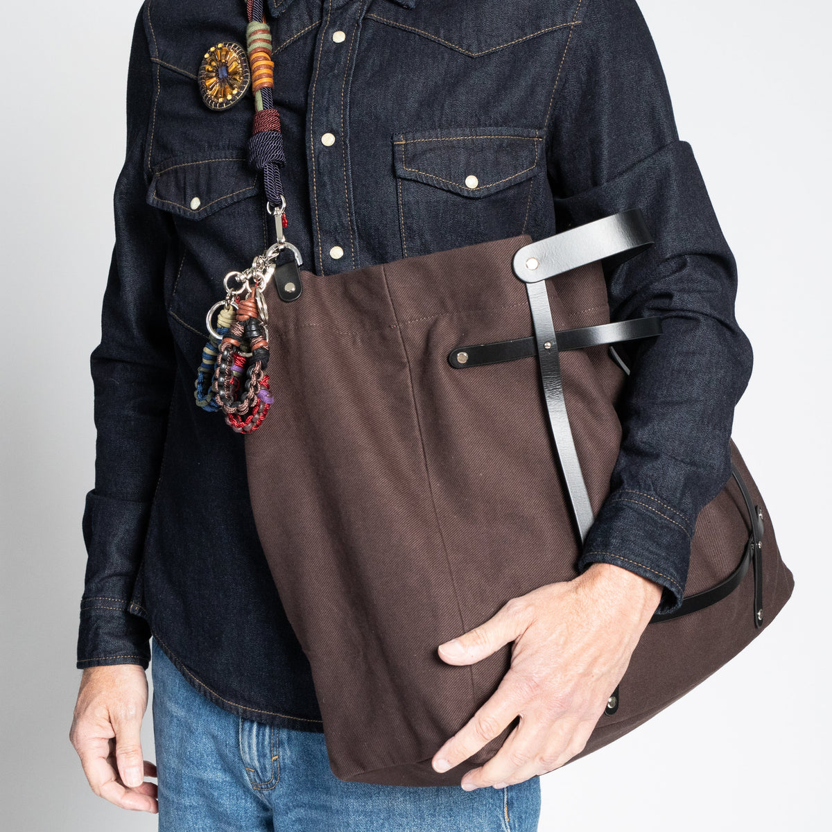 A model carrying cross body the chocolate with black leather straps weekender bag. 