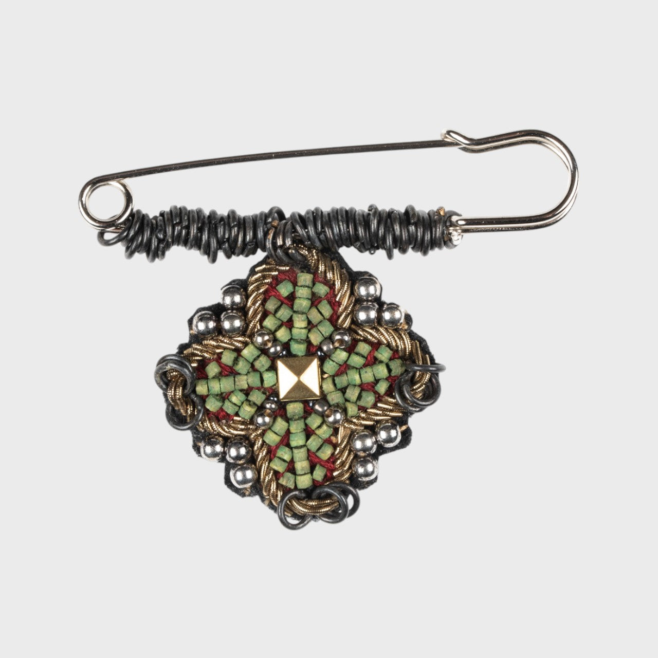 An embroidered pin with red and green details. 