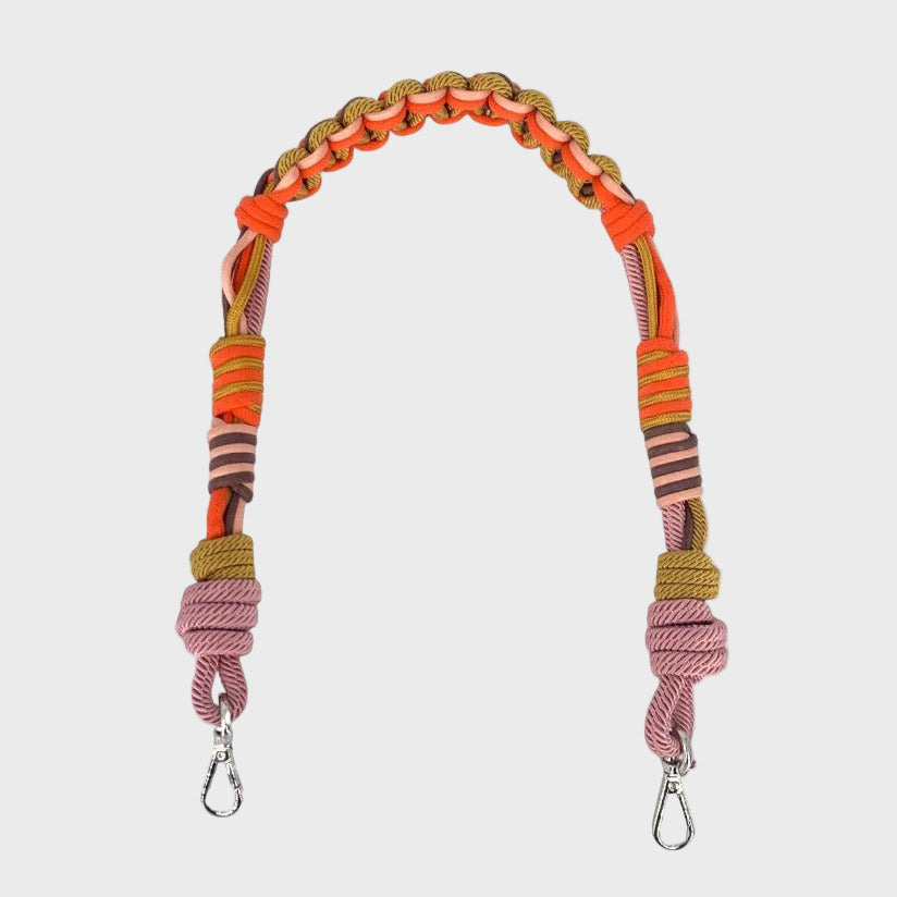 Multicolored braided macramé bag strap in orange, soft pink, and soft yellow with metal hooks on a light gray background.