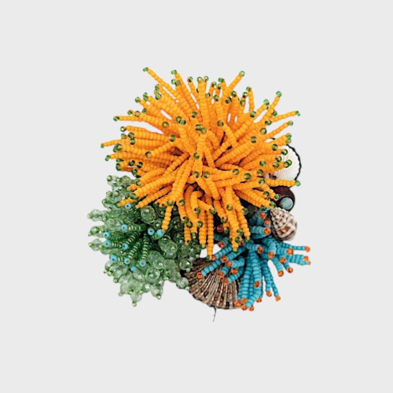 A shell embroided brooch with orange, green, and blue bead embellishments on a light gray background