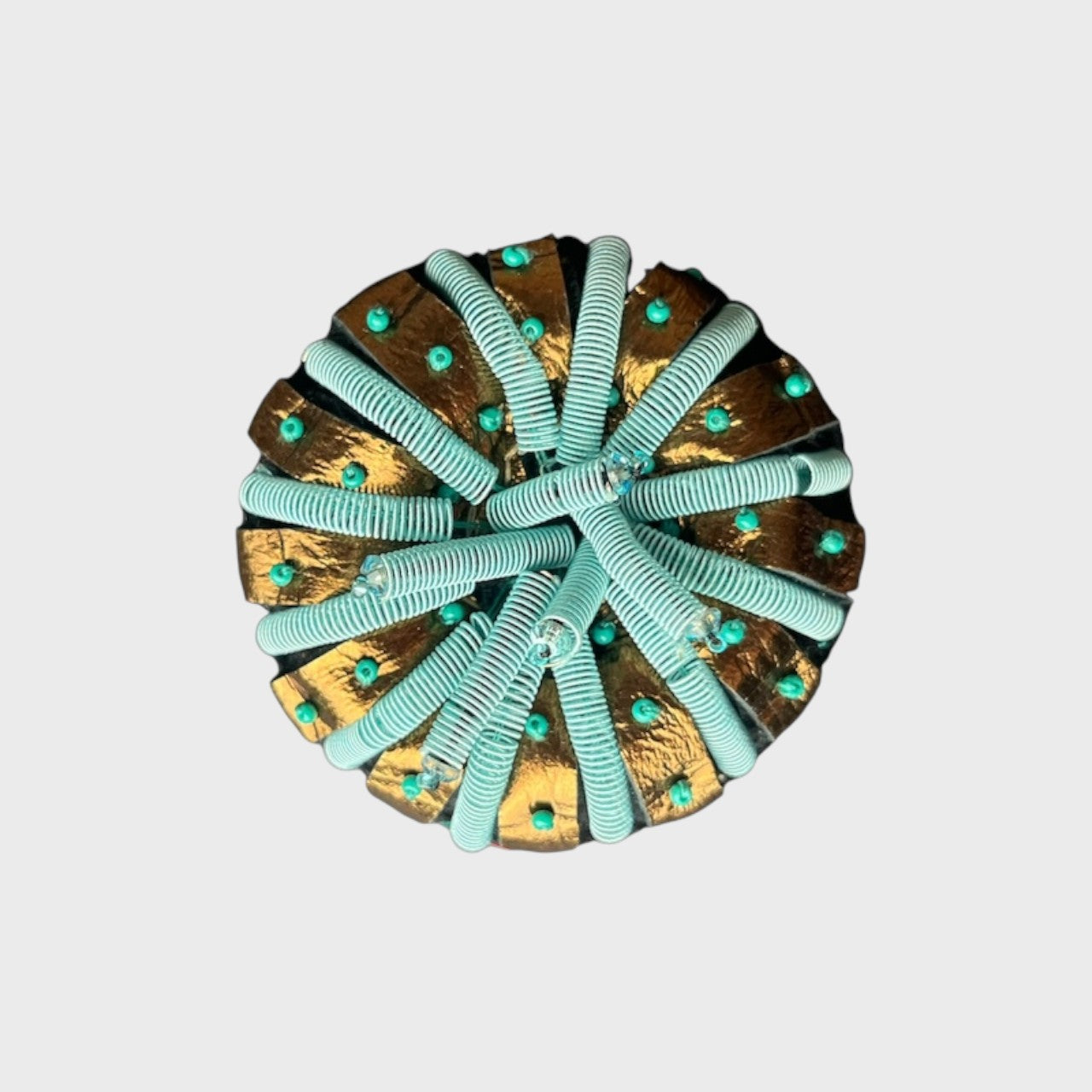 An embroidered brooch representing a cupola shell with blue and gold details. 