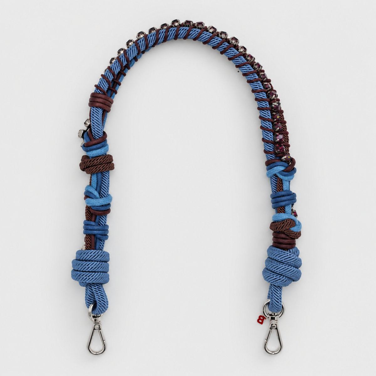 Macramé Blue and brown woven strap with purple rhinestones with metal hooks on a white background