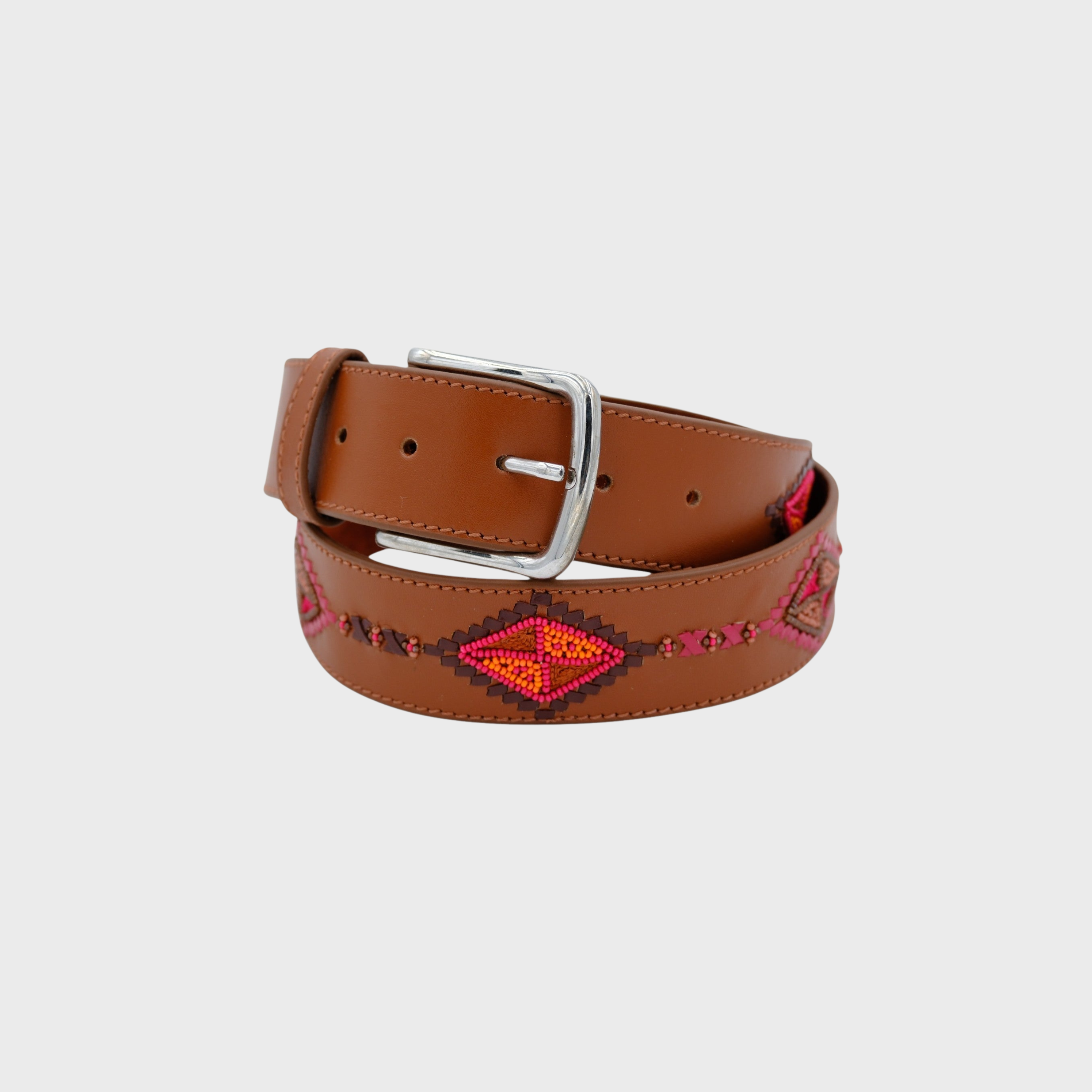 A brown leather belt with a silver buckle, featuring a Southwestern-style geometric pattern in red, orange, and pink on the strap, coiled on a light gray background.