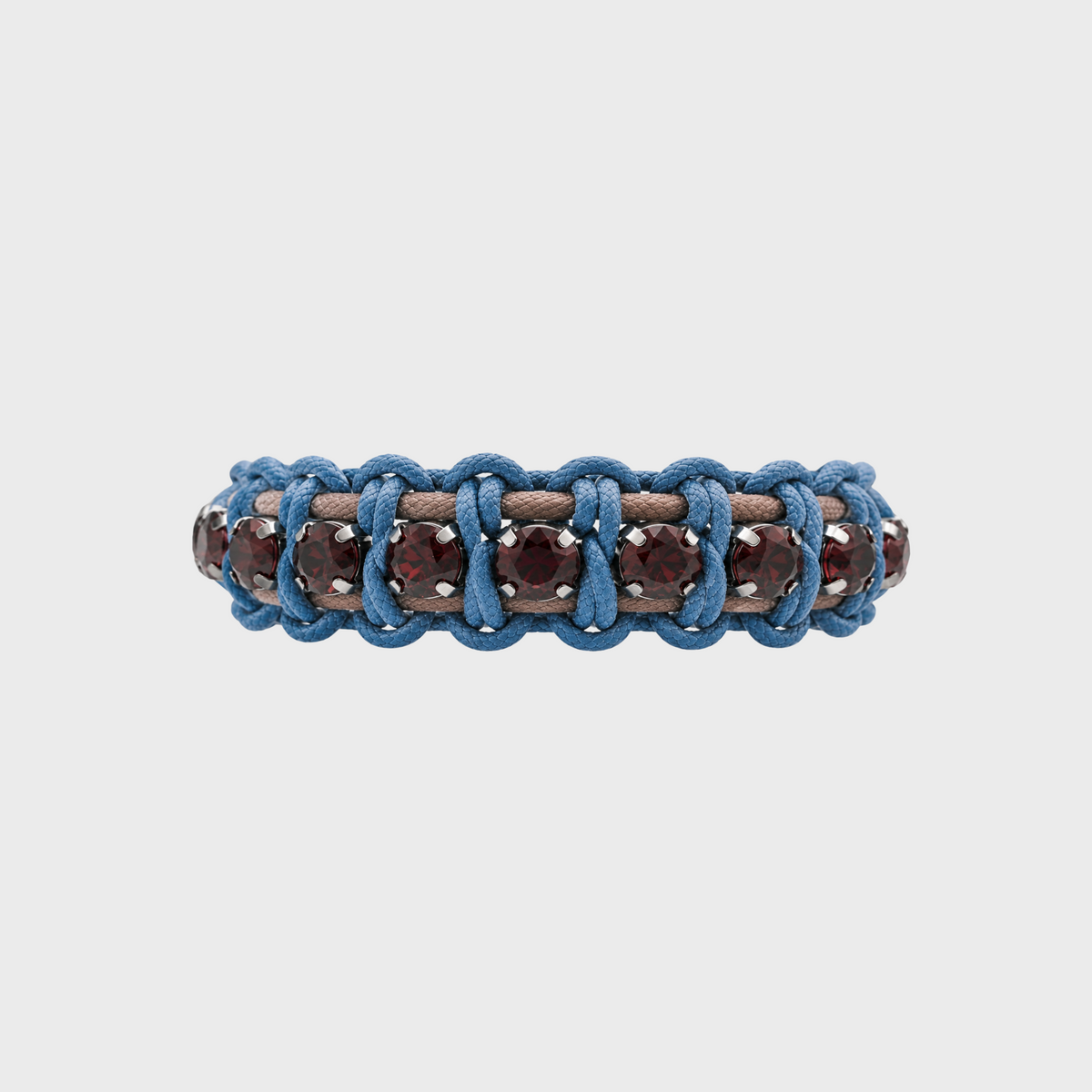 A detail photo of a handmade macrame bracelet featuring blue braided cords, brown leather loops, and faceted dark brown gemstones on a light gray background.