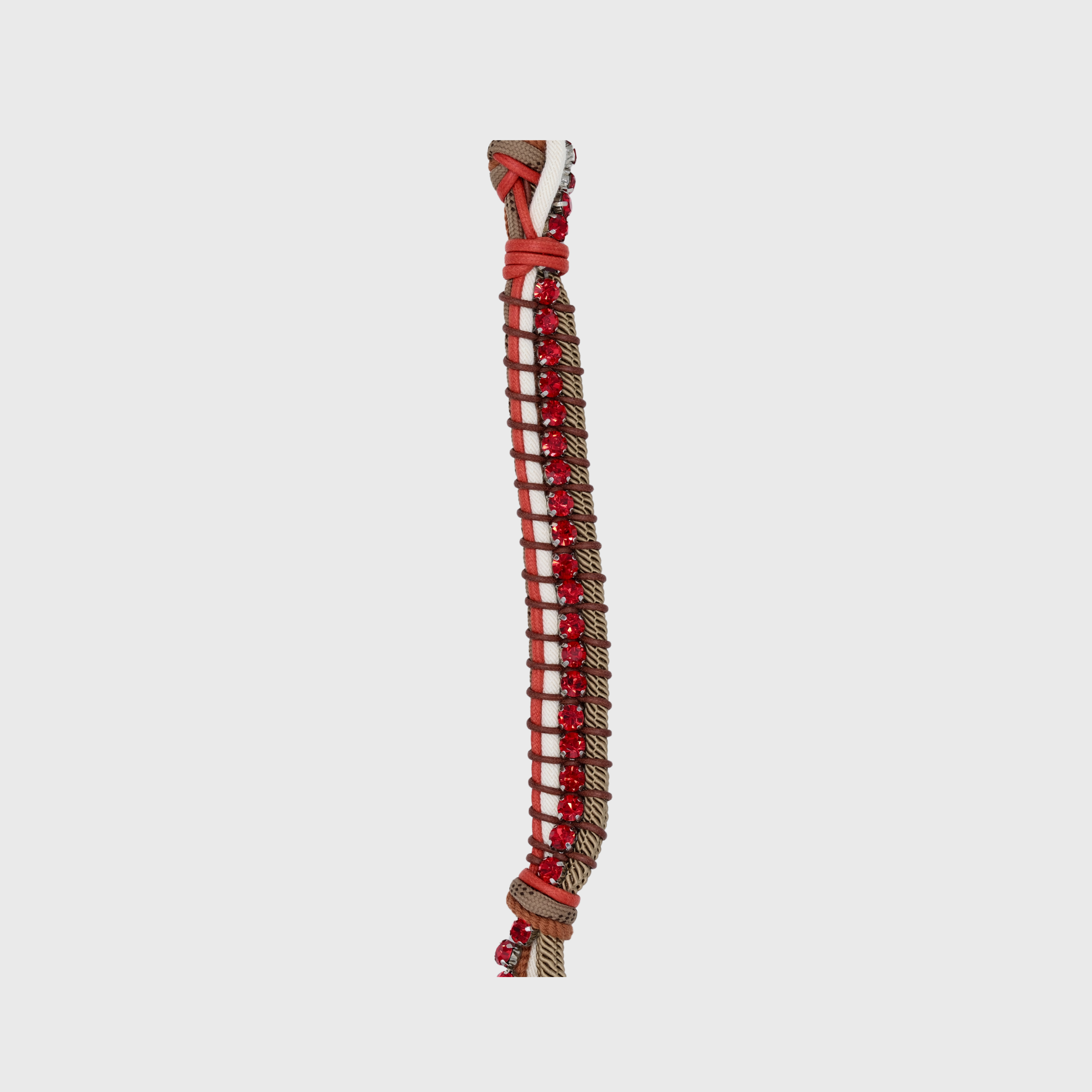 Close up of the multicolored braided macramé bag strap in orange, brown, and white, featuring some red colored beads and shown on a light grey background.