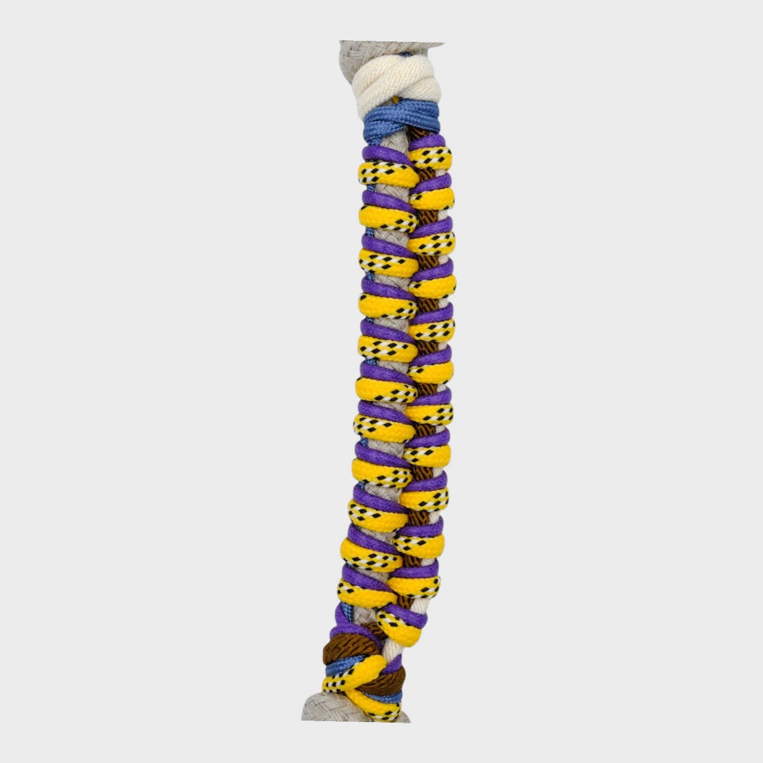 Close up of the multicolored braided macramé bag strap in bright yellow, dark green and purple, with white, shown on a light gray background.
