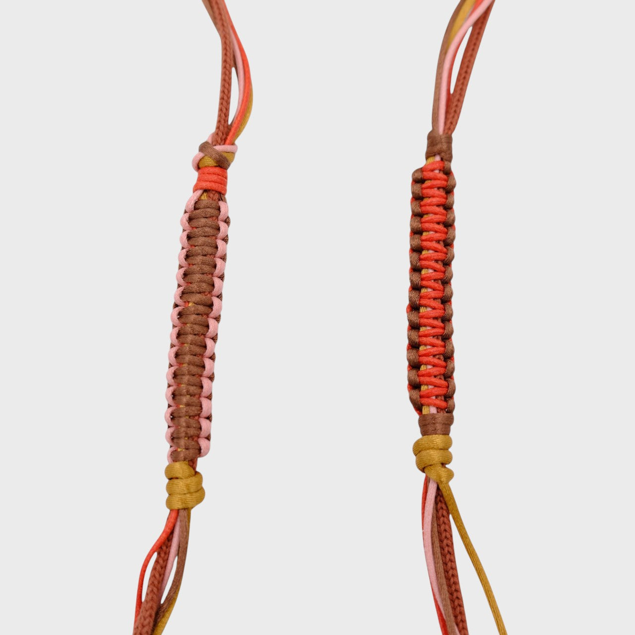 Detail of the brown, red, light pink and yellow phone lanyard. 