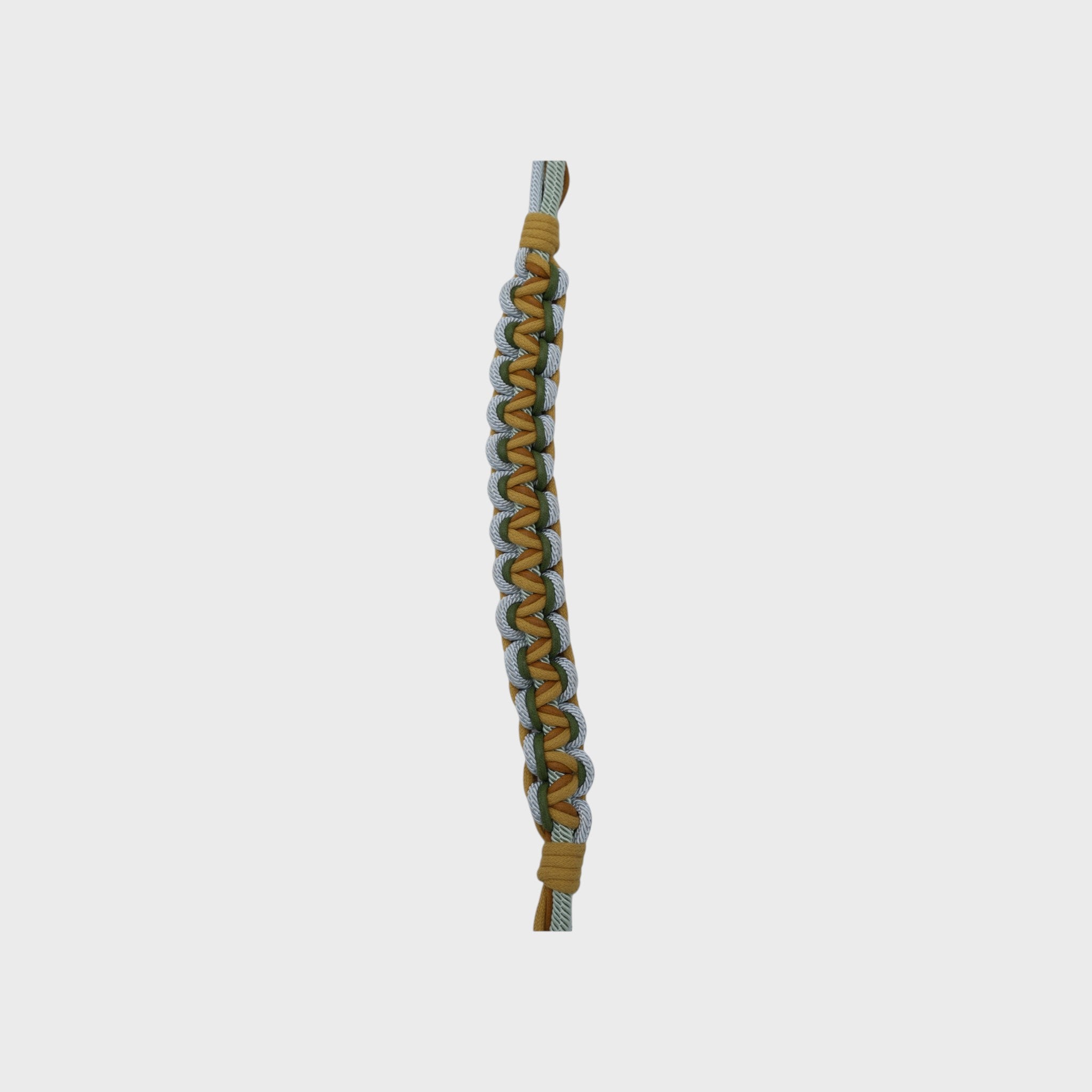 An up close photo of a multicolored braided macramé bag strap in yellow, light blue, and green with metal hooks on a light gray background.