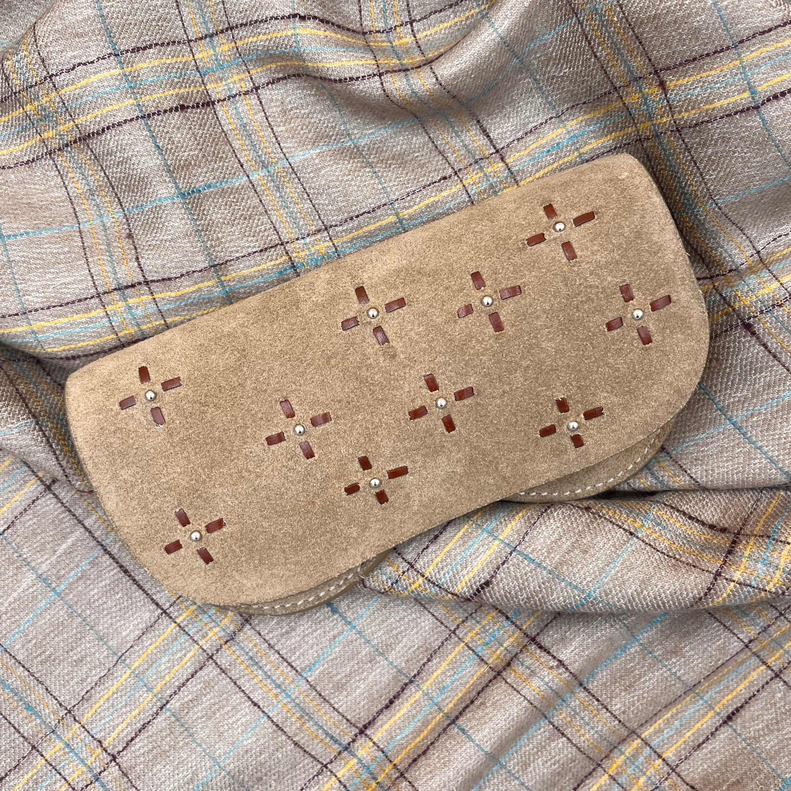 A brown suede leather dots glasses case put on a grey blanket. 