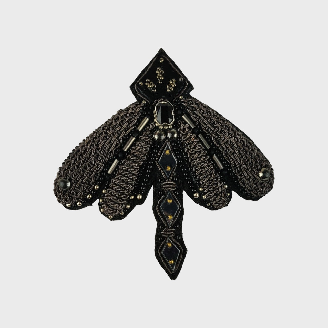 An embroidered brooch representing a dragon fly in black. 