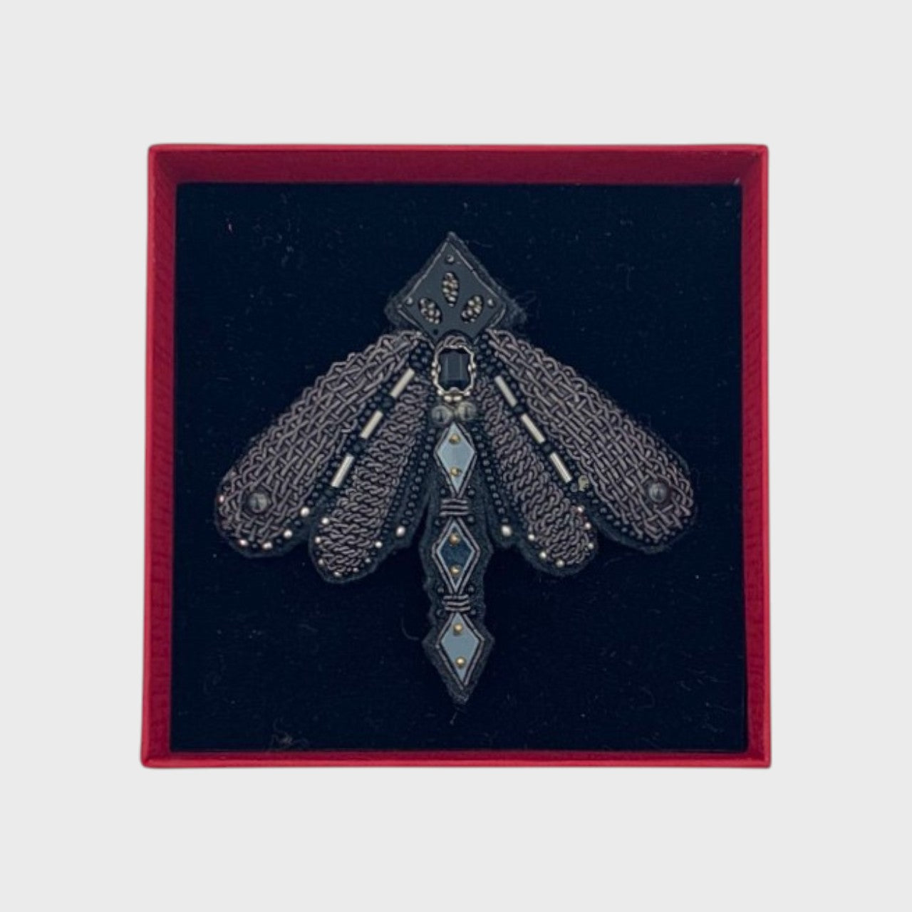 An embroidered blach brooch representing a dragonfly in a box. 