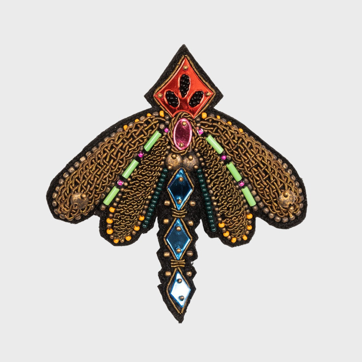 An embroidered brooch representing a dragonfly with blue, green, yellow and bronze details. 