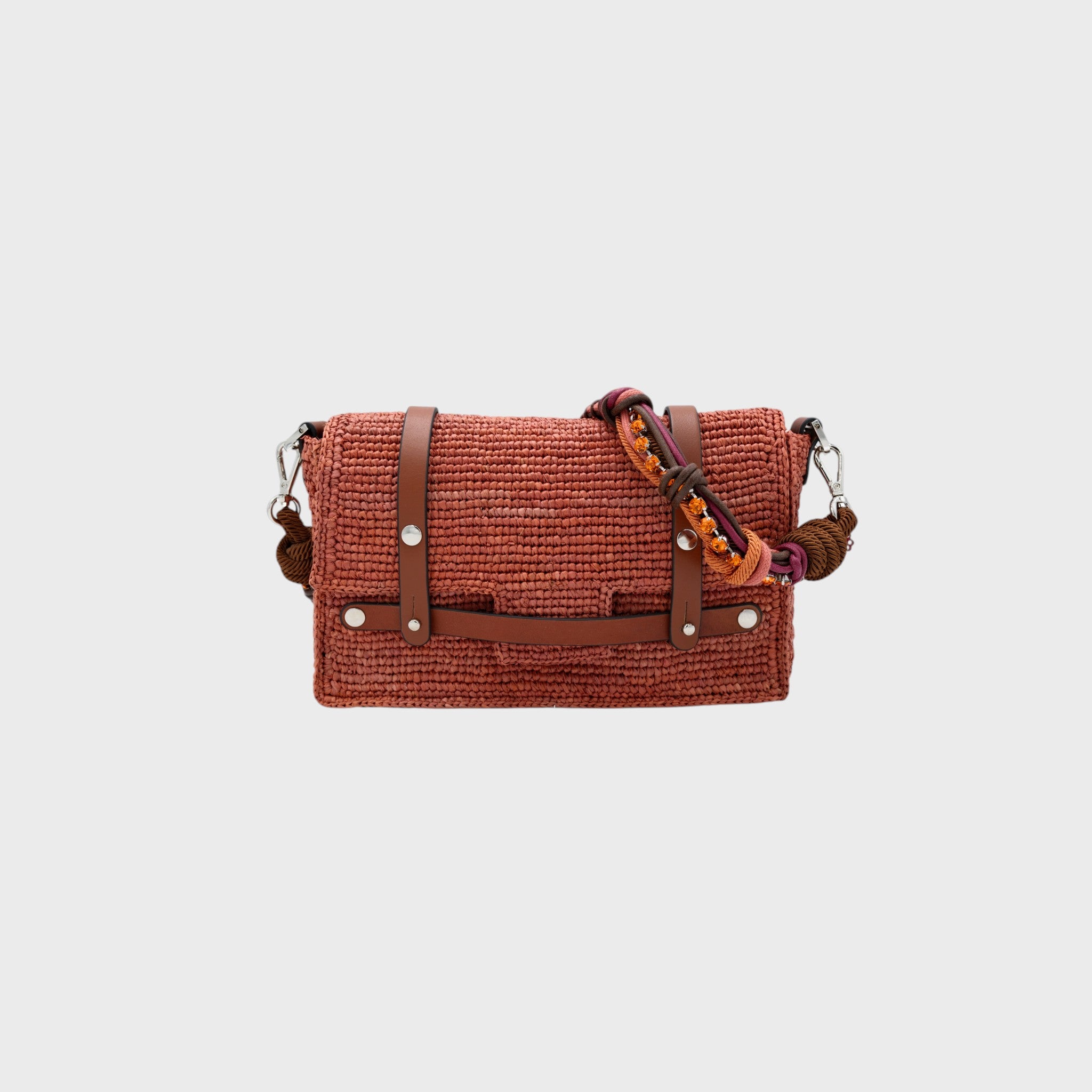 A dusty pink raffia shoulder bag with brown leather straps and a colorful macramé braided strap featuring brown, pink and orange beaded stones. 