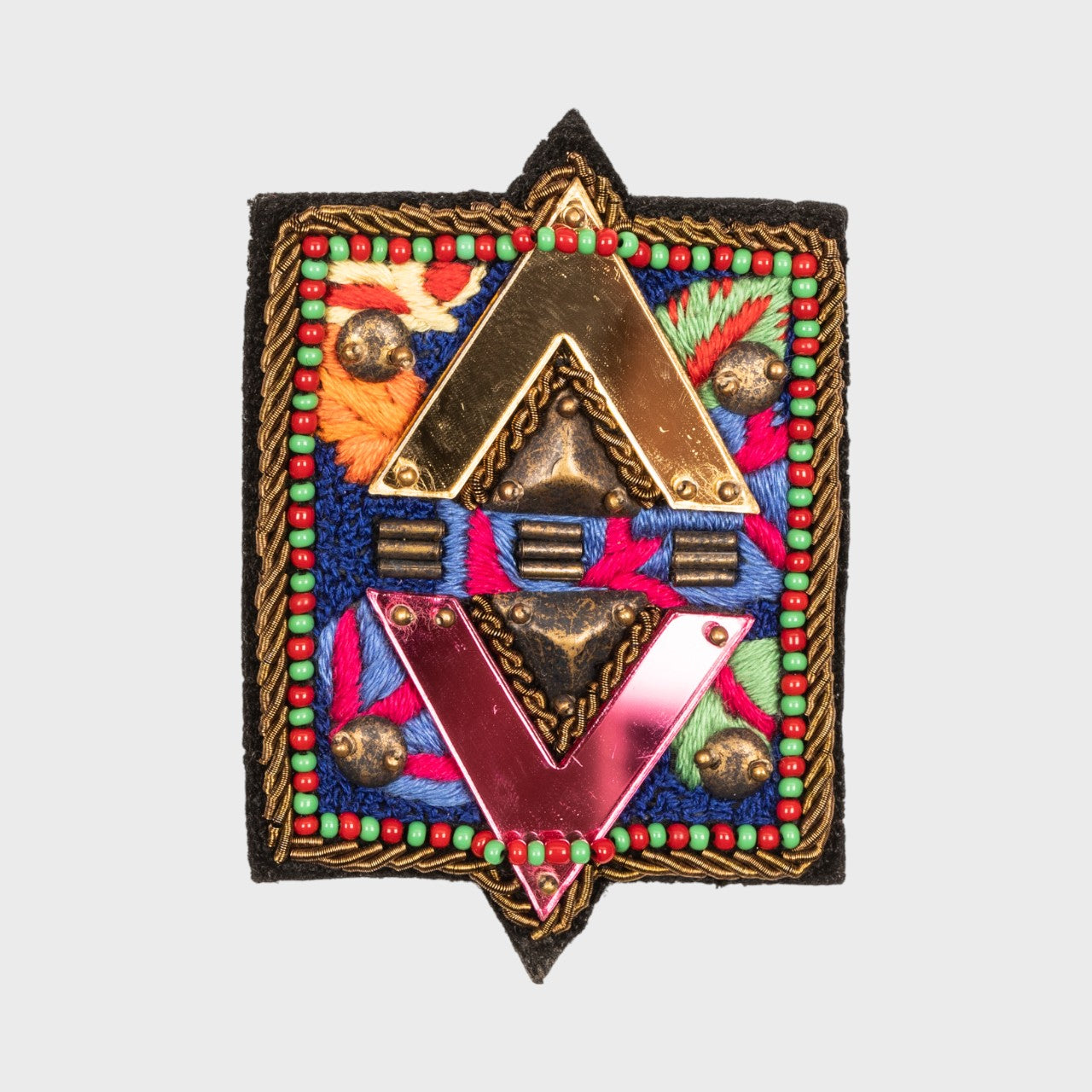 An embroidered brooch symbolizing elements with pink, green, blue and orange details. 