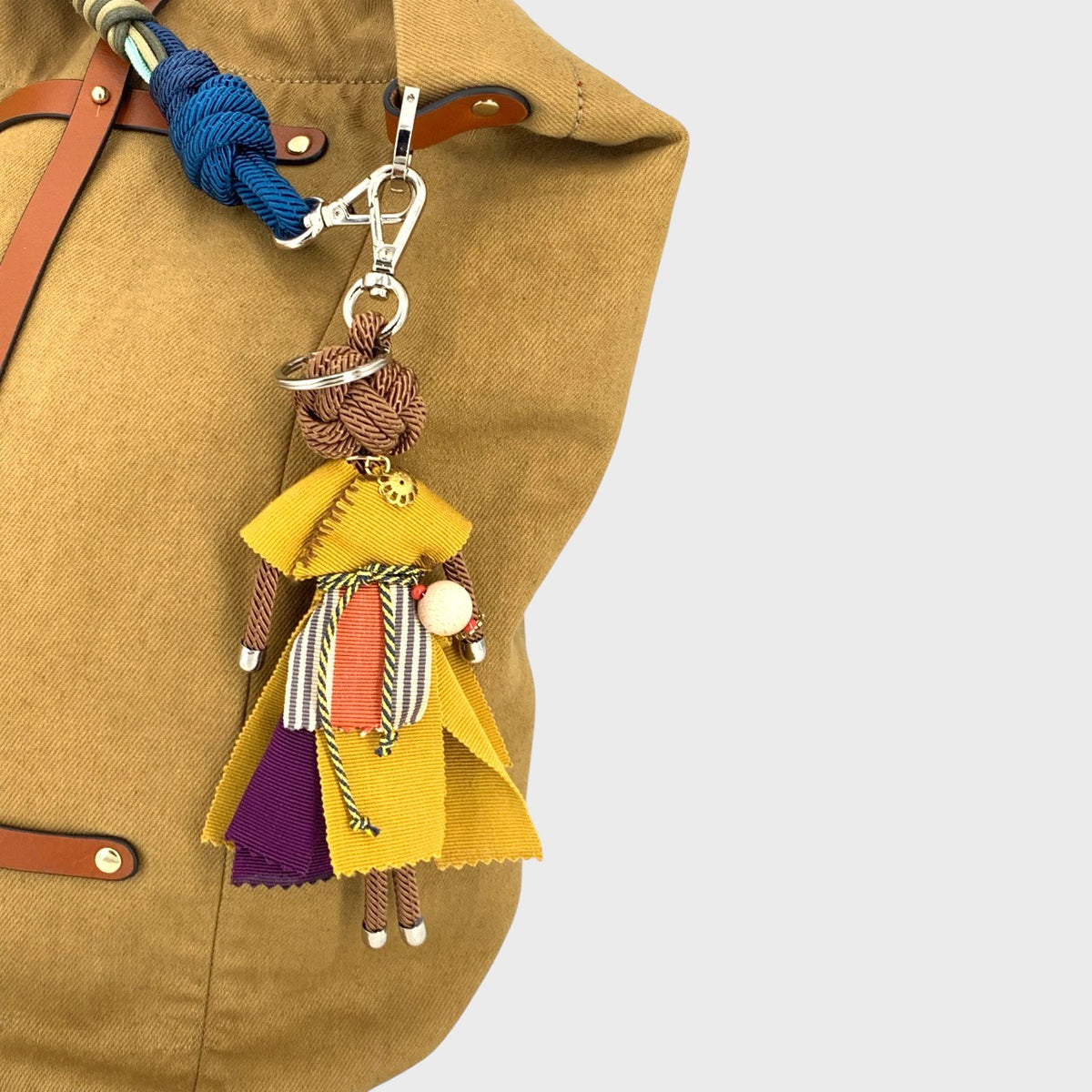 Colorful keychain with a macramé character design attached to a brown bag.