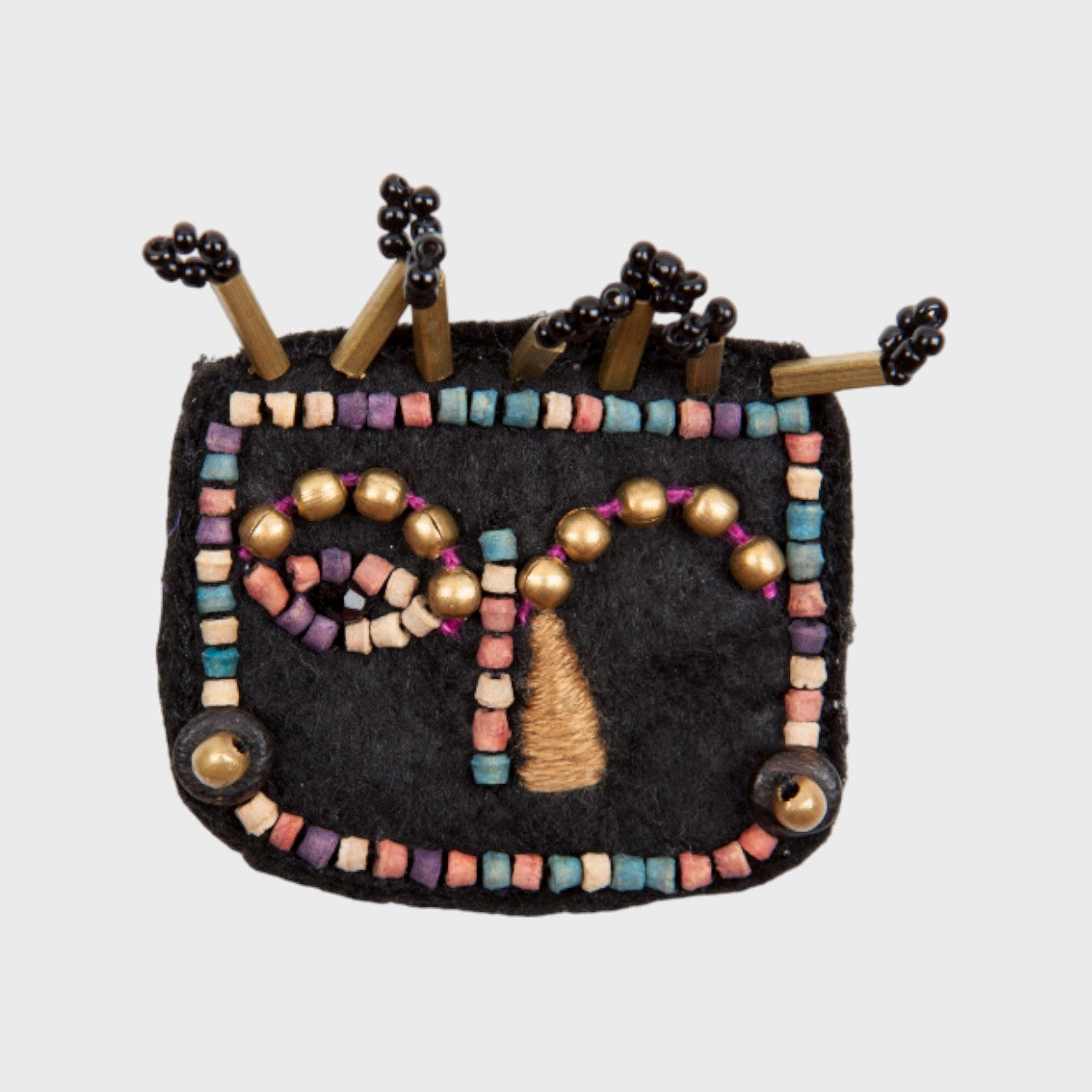 An embroidered brooch representing a face with beige details. 