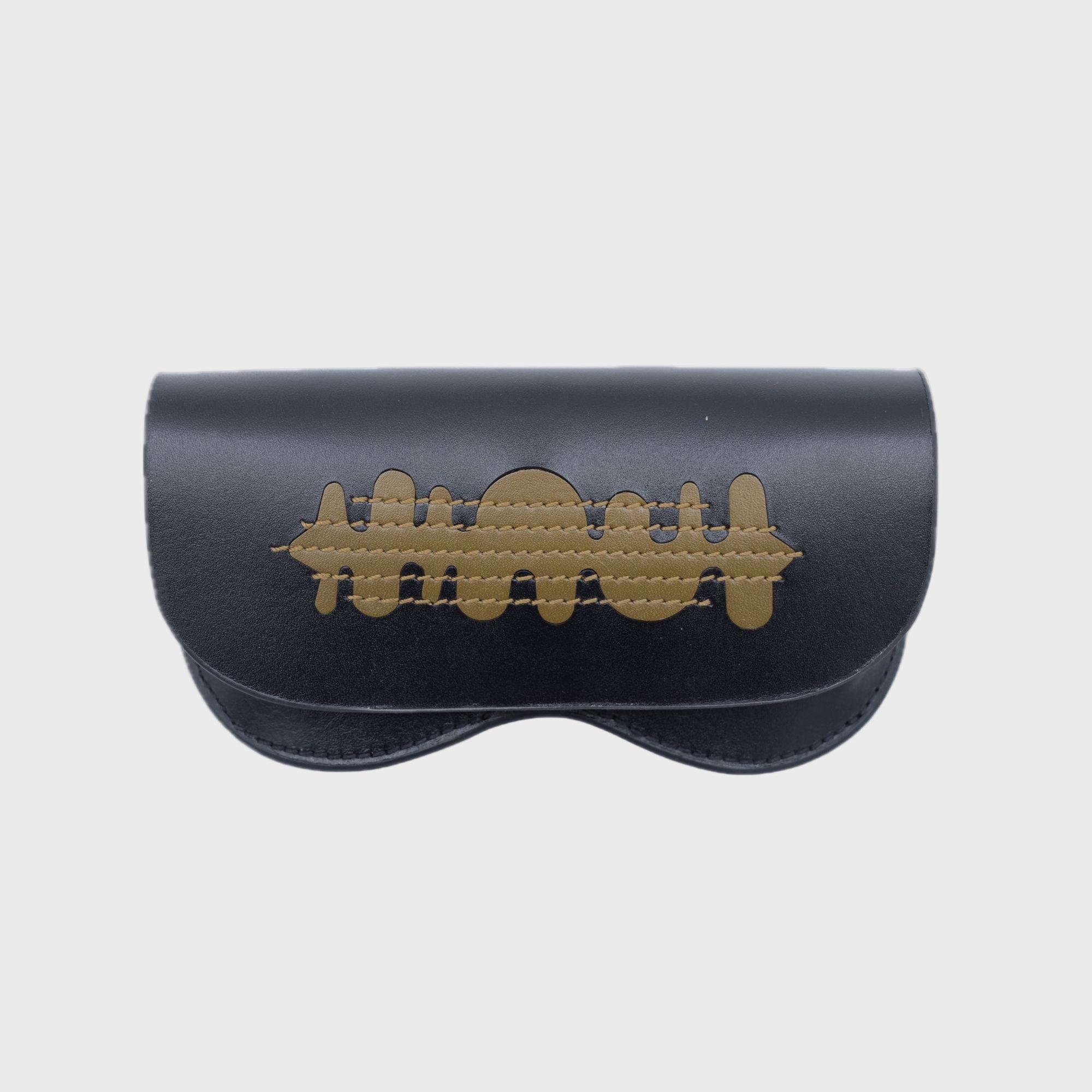 Black glasses case with golden details embroidered on it. 