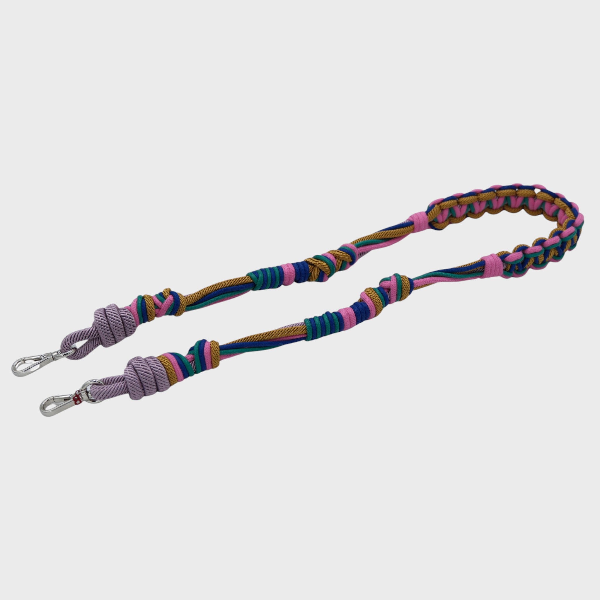 Multicolored braided macramé bag strap in bright pink, blue, and yellow with metal hooks on a light gray background.