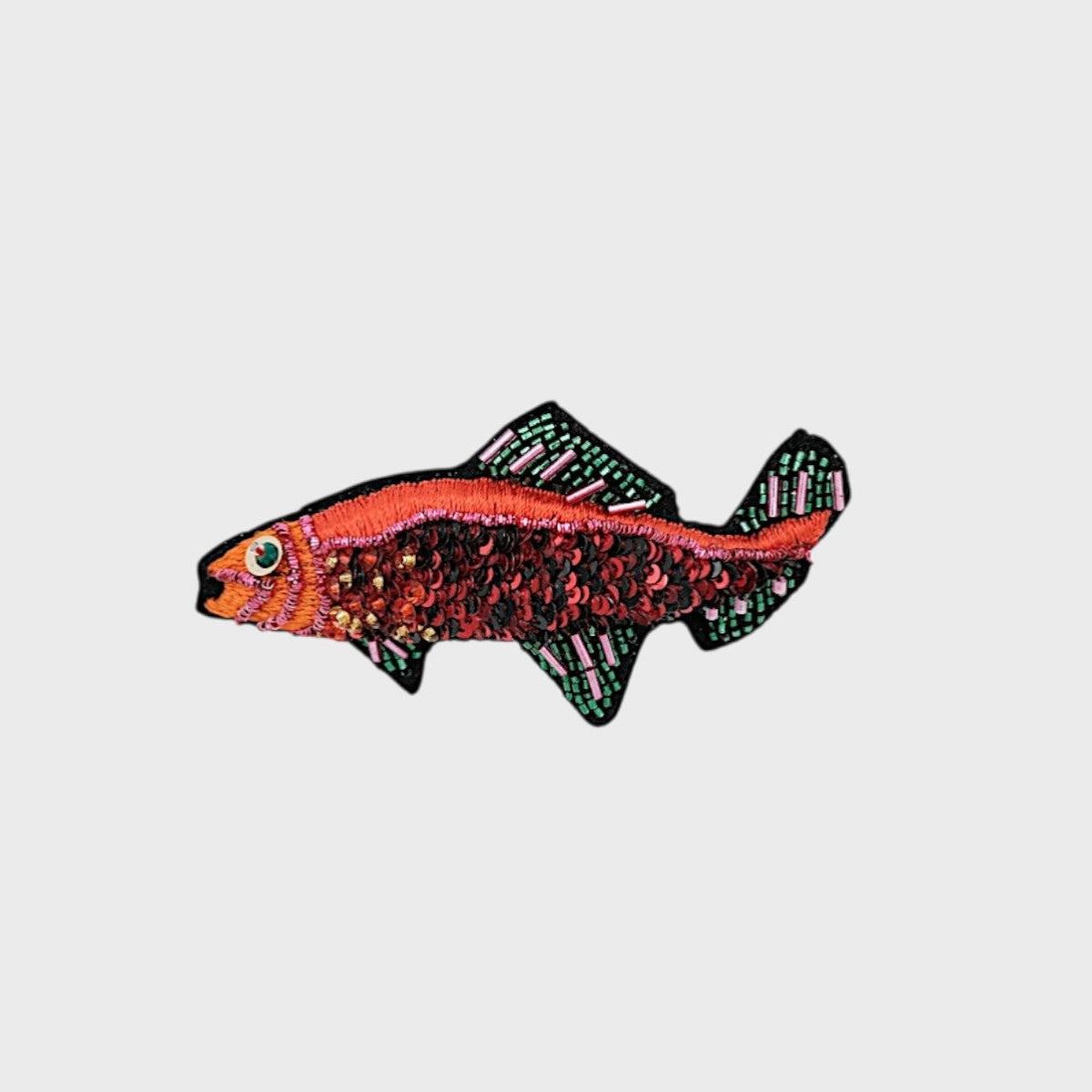 An embroidered red fish brooch with green and pink details. 