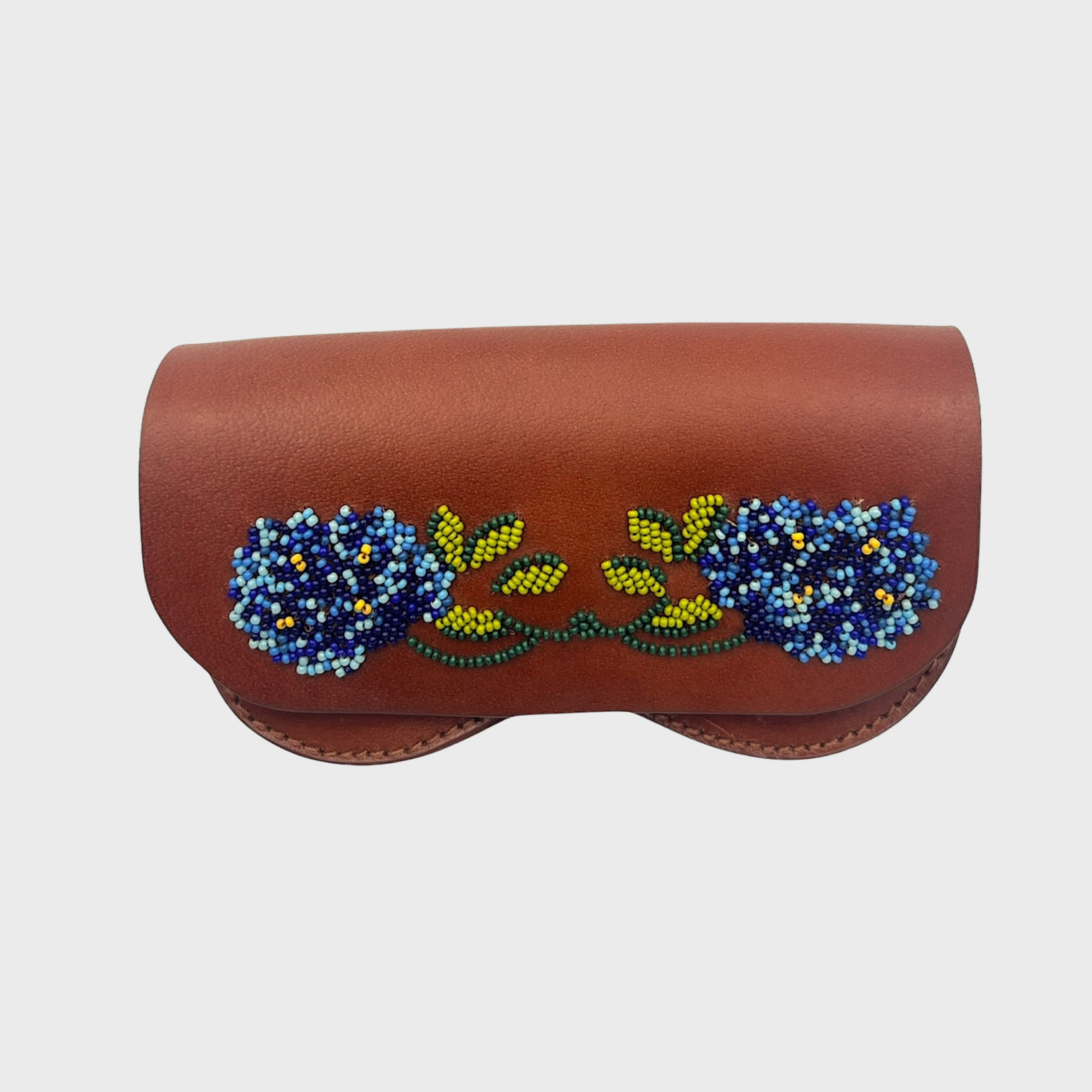 A brown leather eyeglasses case featuring a detailed beaded floral design in blue, yellow, and green across the center, set against a plain light gray background.