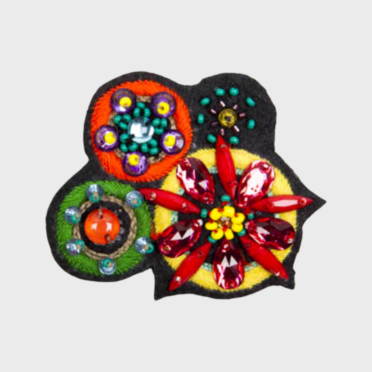 An embroidered brooch representing four flowers with yellow, orange, red and green  details. 