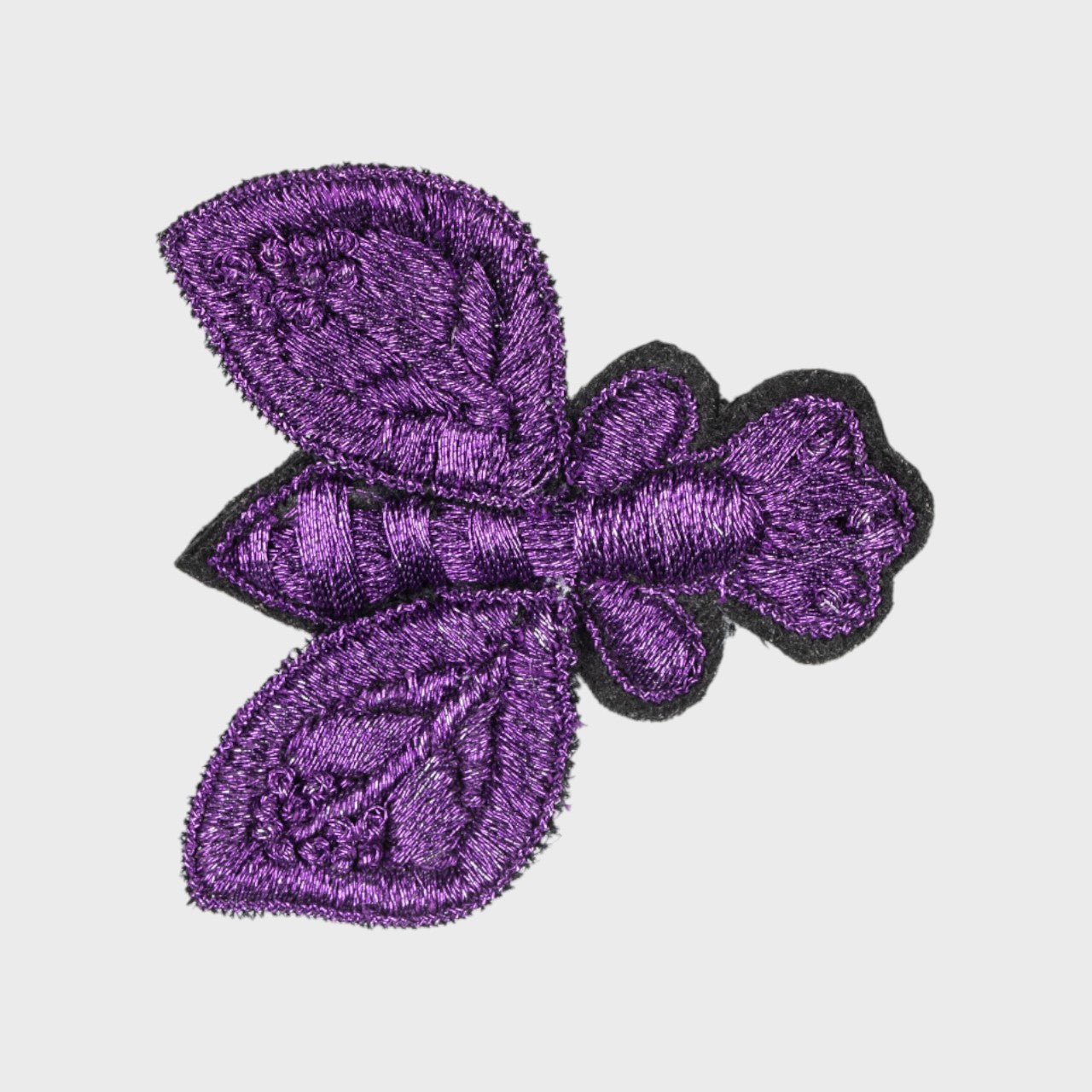 An embroidered brooch representing a purple fly with black details. 