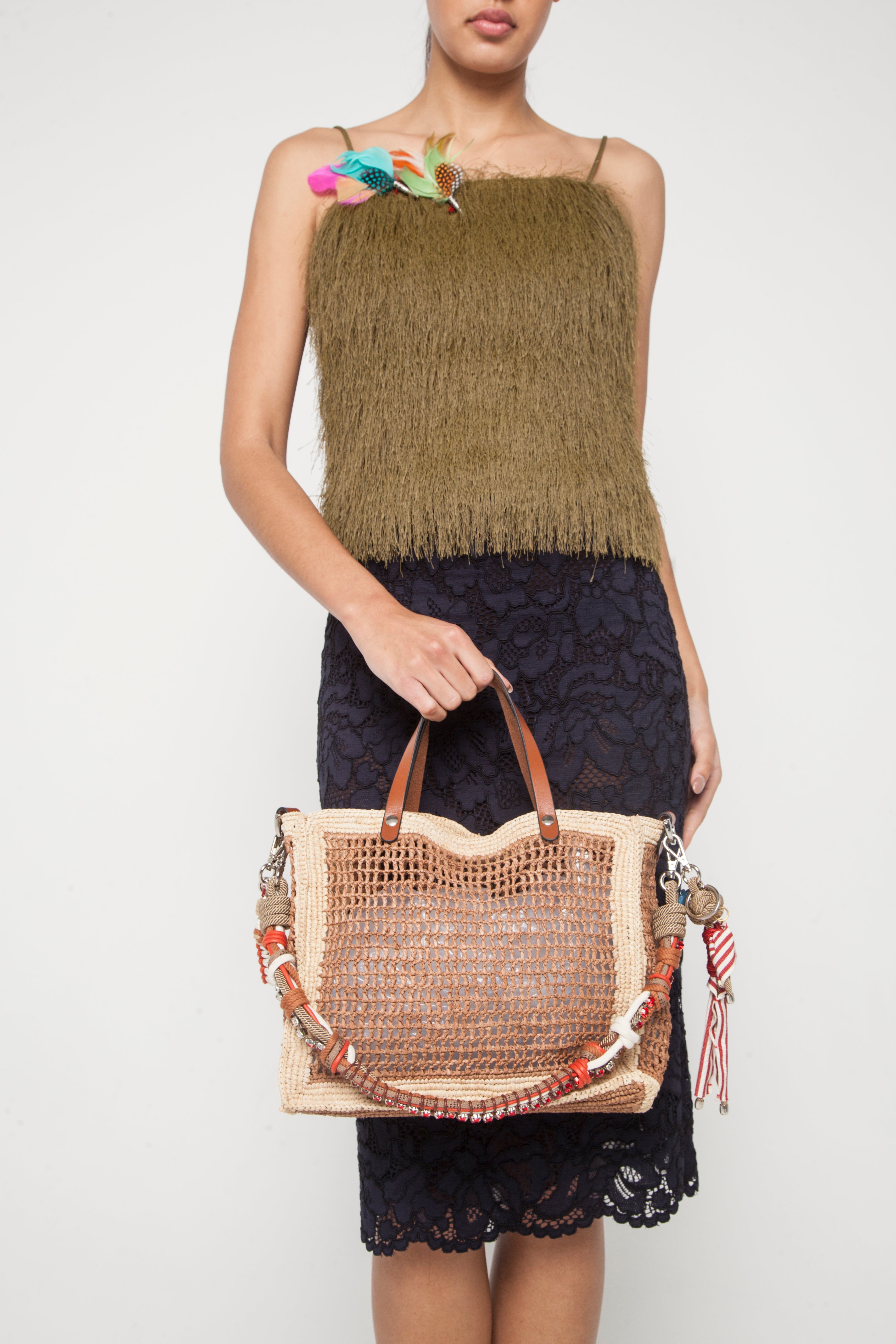 A model facing the picture carrying the natural and tea cabas handbag with a strap and a key ring. 