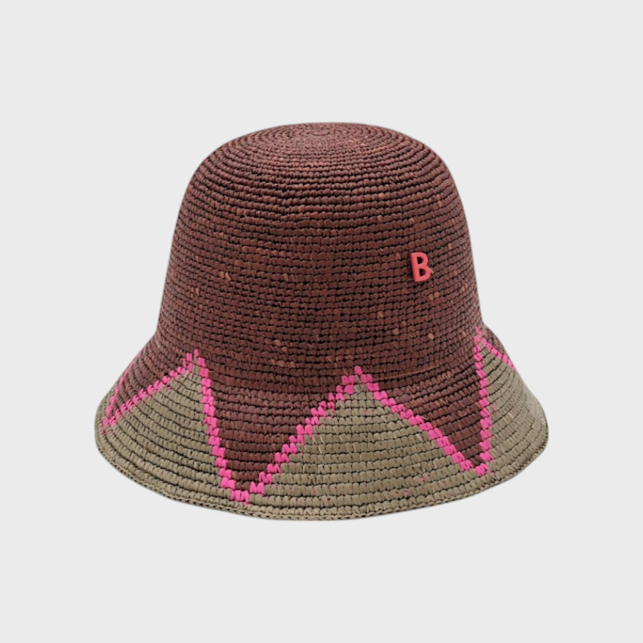 Two-toned raffia bucket hat with pink and green accents on a light gray background