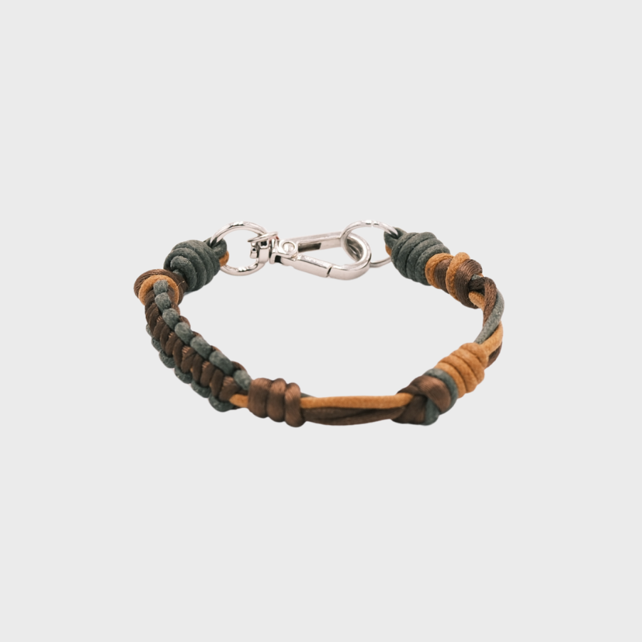 A thin braided bracelet with green and mustard macramé, featuring a silver metal  clasp. 