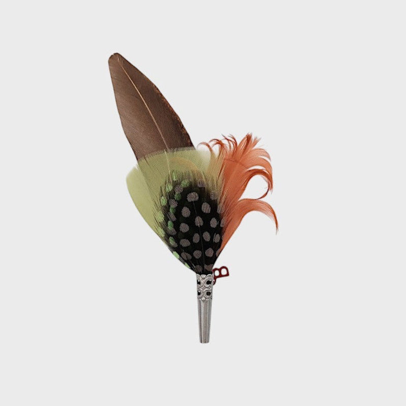 Green, grey and red feathered brooch on a light gray background