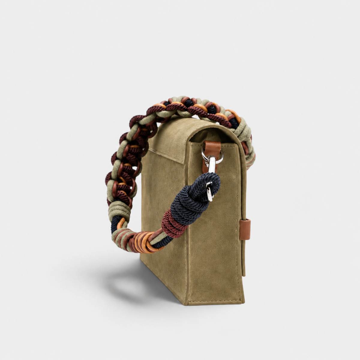 A green suede rectangular bag with a colorful macramé strap shown on its side. 