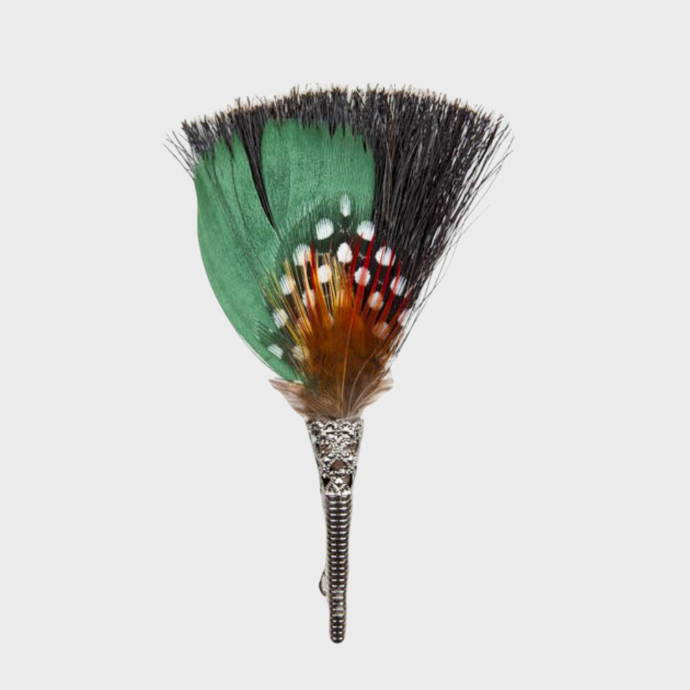 Grey, green and brown feathered brooch on a light gray background