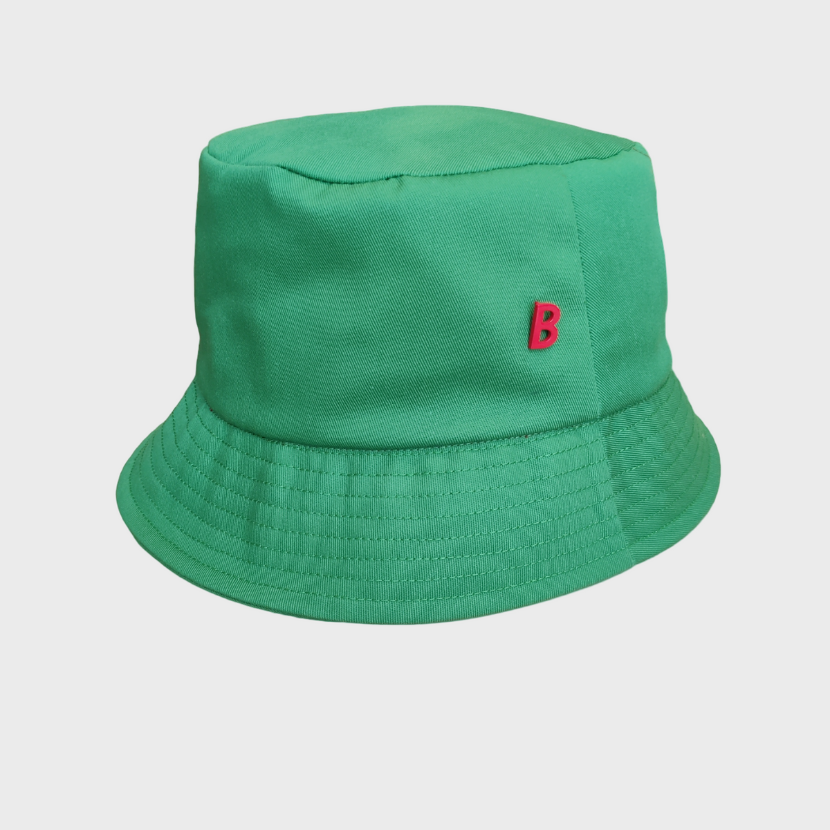 Green cotton bucket hat with a red B logo pinned on it on a light gray background