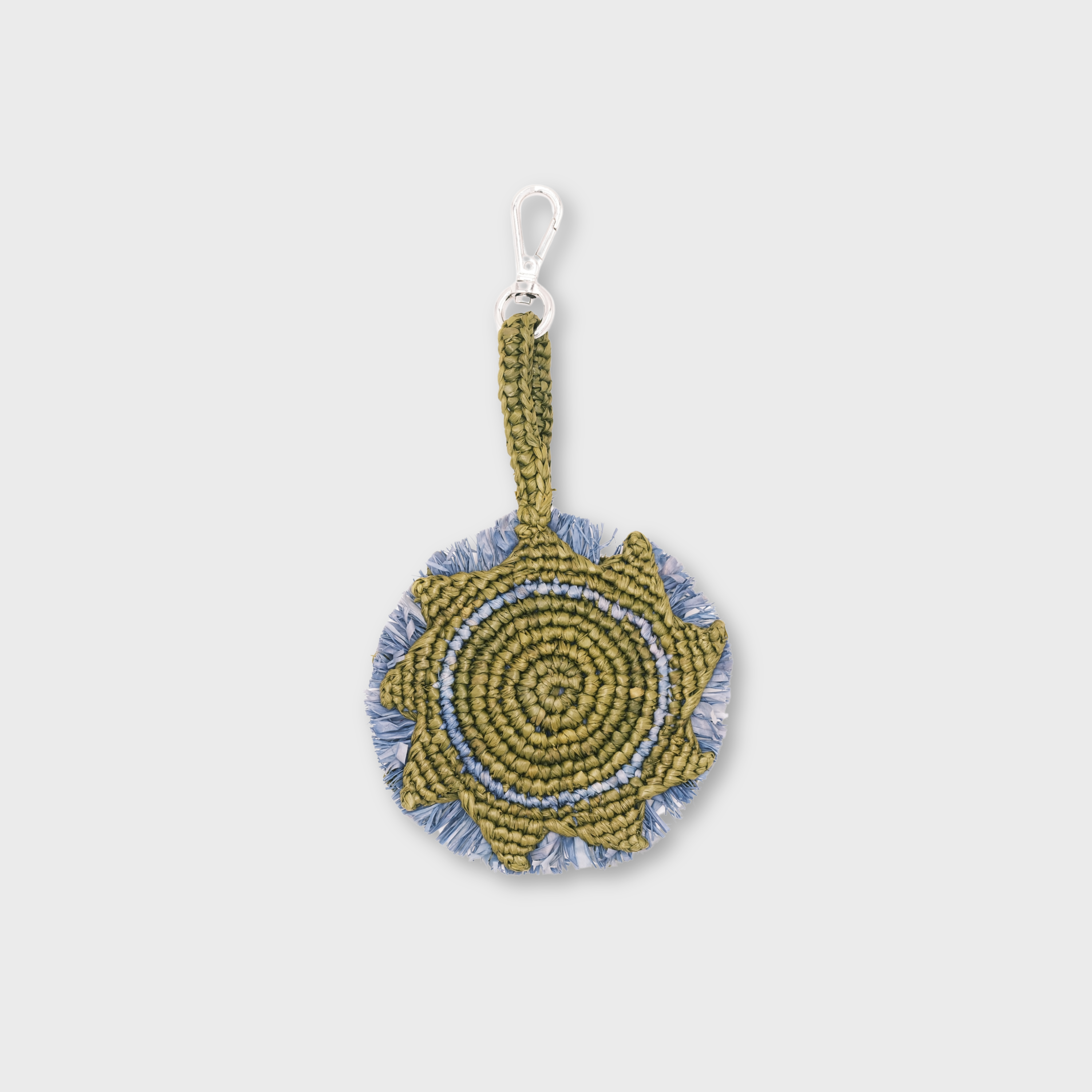 A handmade circular raffia keychain  in olive green and light blue, representing the sun with a silver metal lobster clasp.