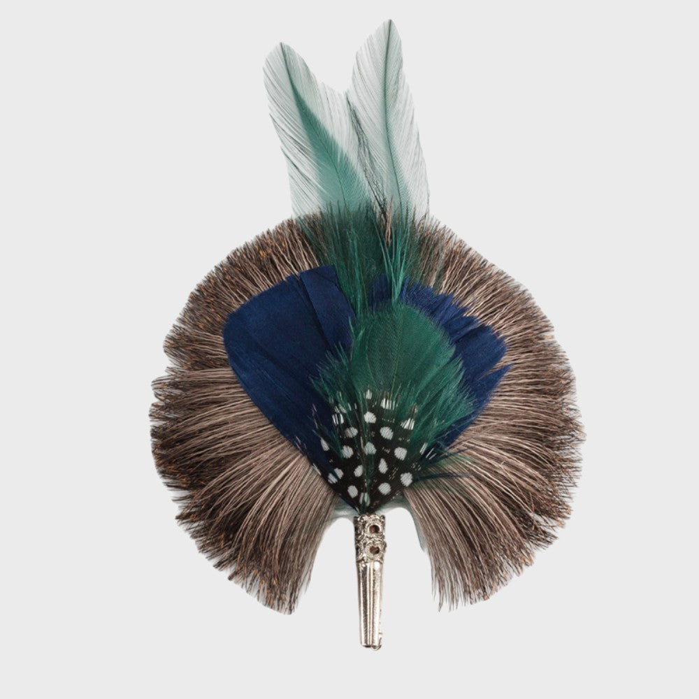 Blue, green and grey feathered brooch on a light gray background