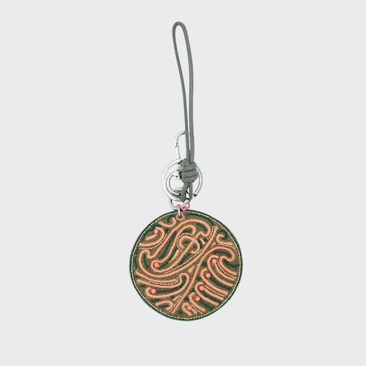 Round decorative keychain with intricate green embroidered design on a white background