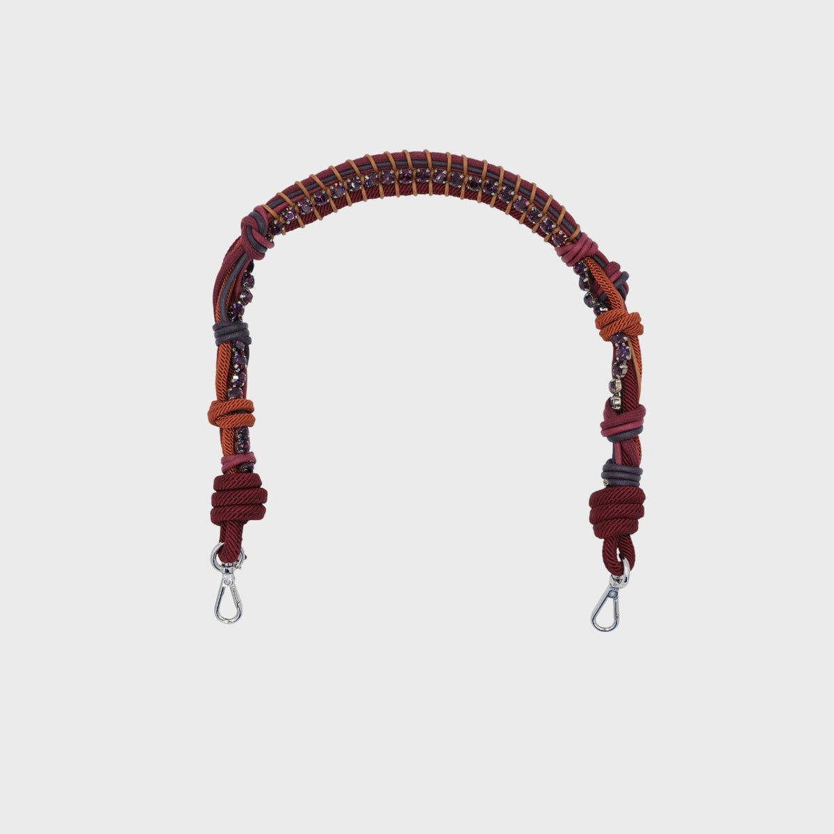 A burgundy macramé bag strap with purple rhinestones on a light grey background. 