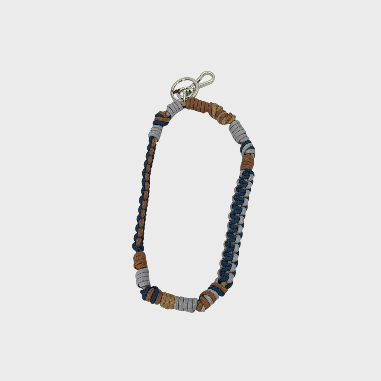 A bohemian-style woven macramé key chain with a silver-tone lobster clasp, featuring brown, blue and grey woven segments on a light gray background.