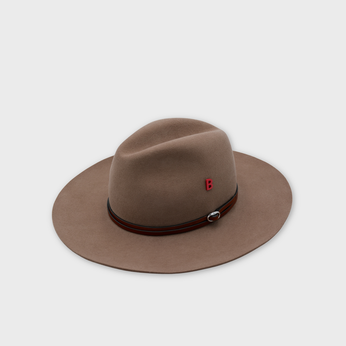 A brown felt wide-brim hat with a dark brown leather band and a small red letter 'B' pin on the side, shown on a light gray background.