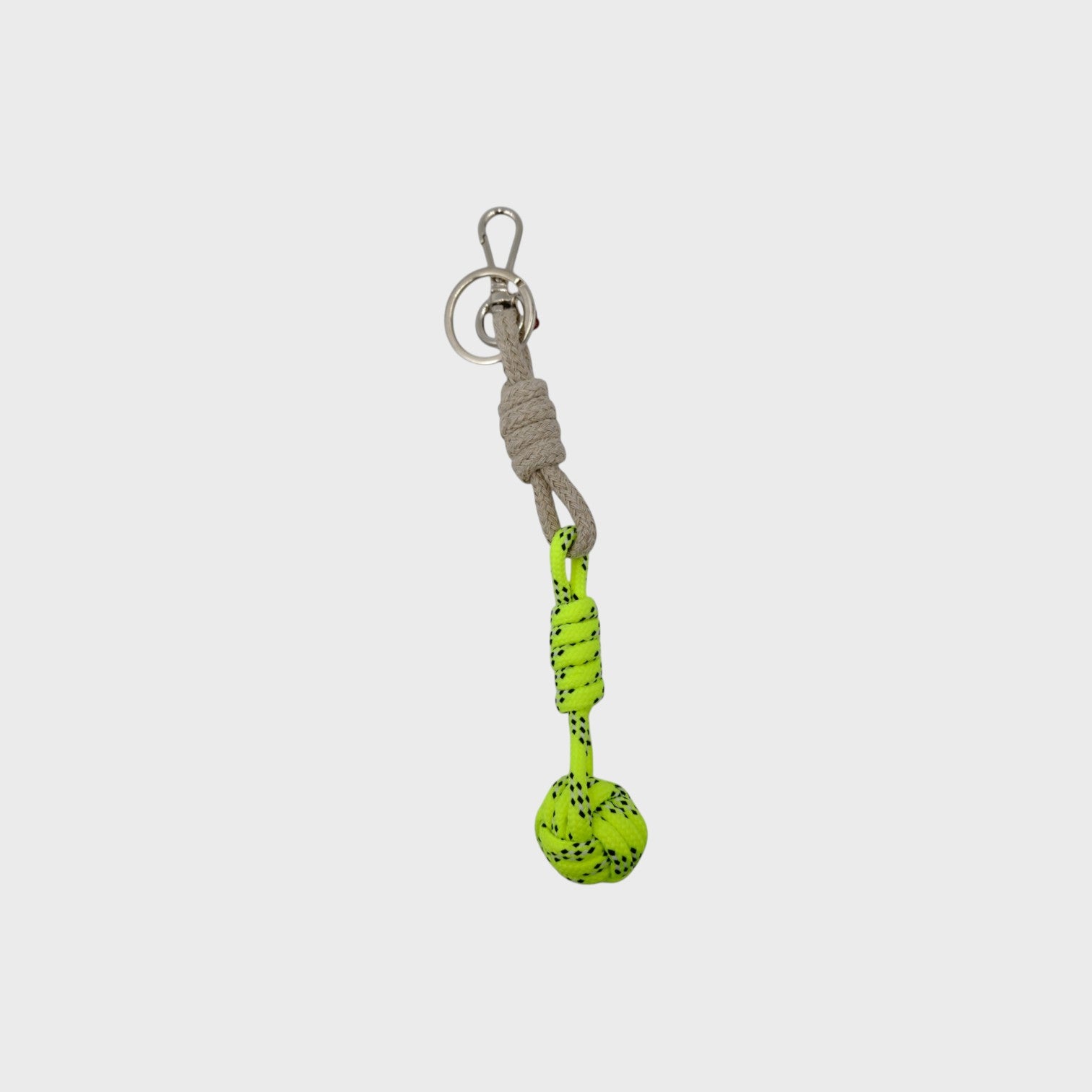 A macramé keychain representing a ball inspired by sailors knots. The straight upper part is grey and the ball part is neon yellow. 