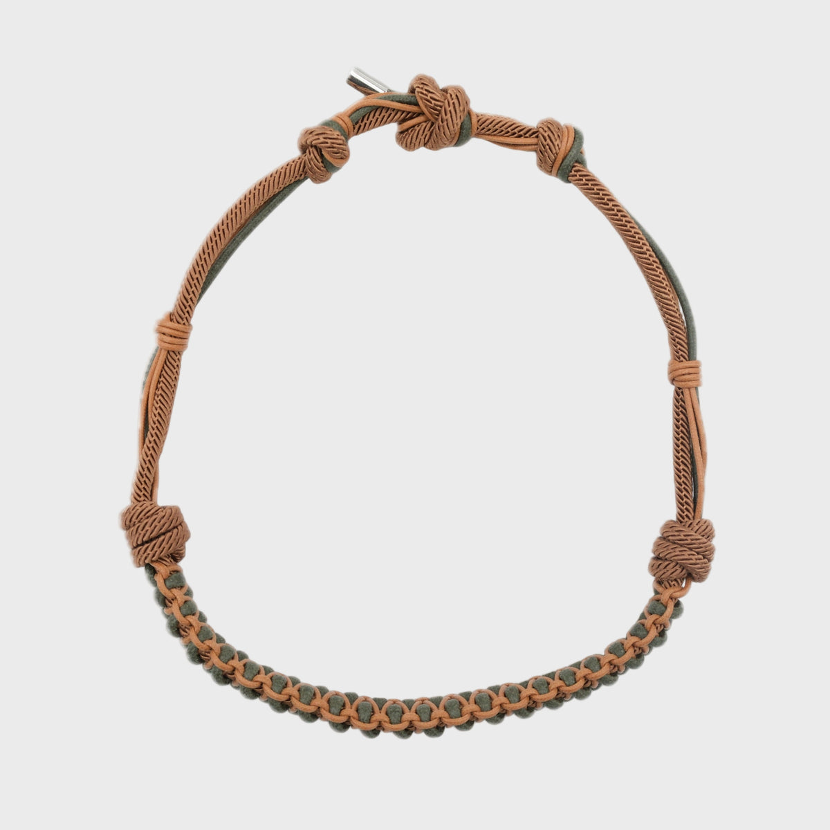 A brown and green macramé hatband on a light grey background. 