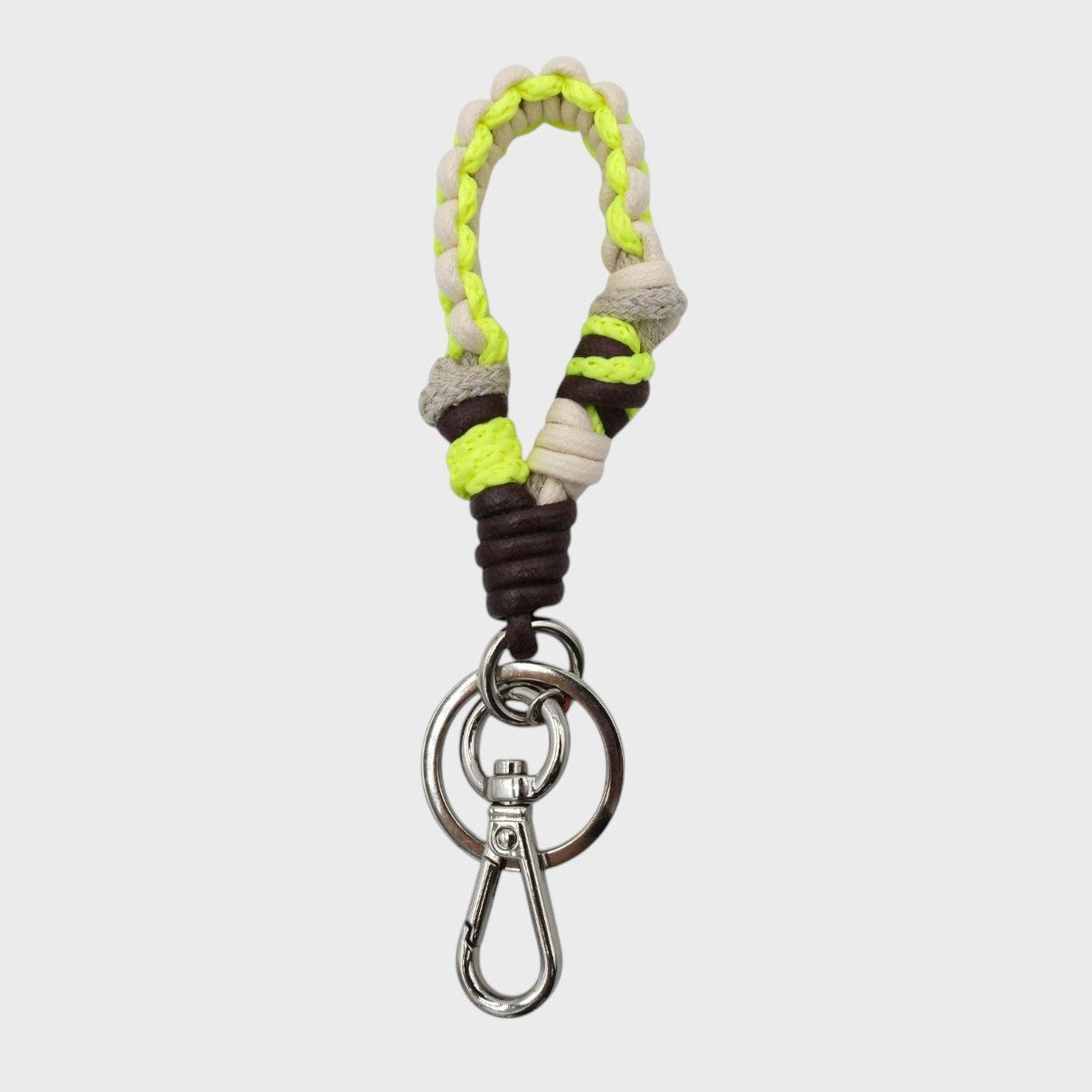 A braided macramé keychain or bag clip in neon yellow, dark brown and beige, featuring a silver metal clasp. 