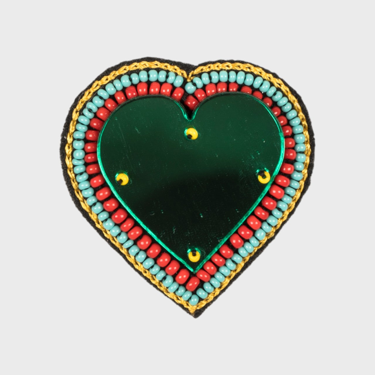 An embroidered brooch representing a heart with a green glass middle and blue and red details. 