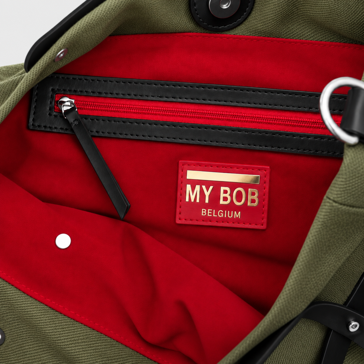 Inside detail of the optimiste tote bag with a red lining and zipper with black leather trim.