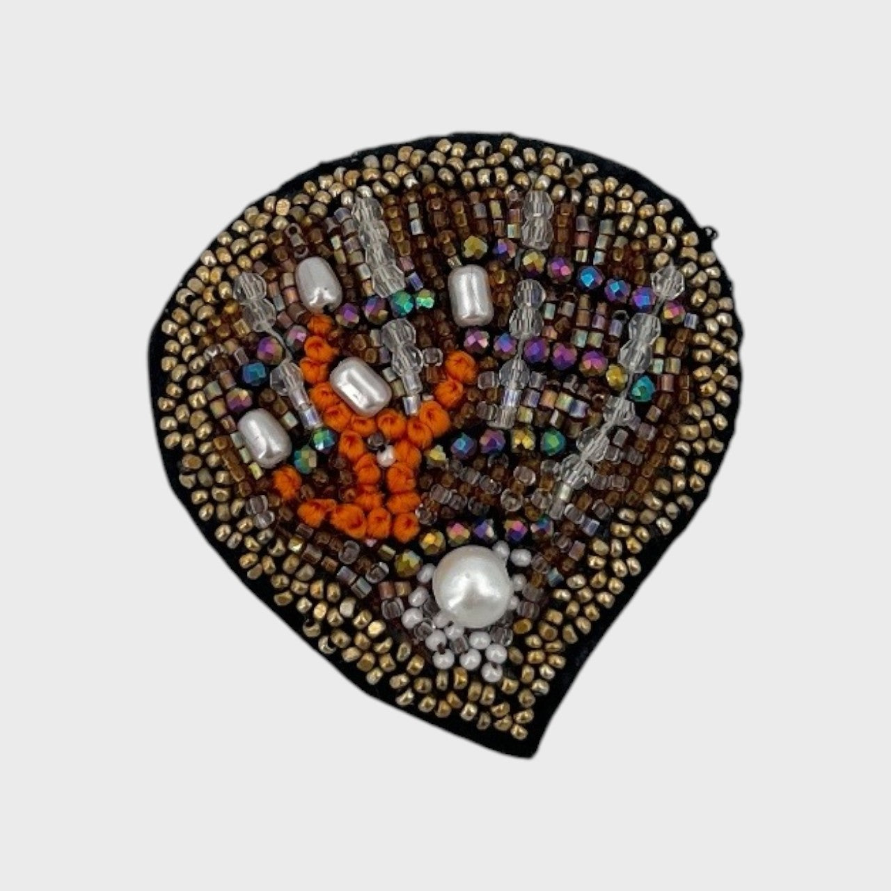 An embroidered brooch representing an oyster with beige, brown and orange details. 