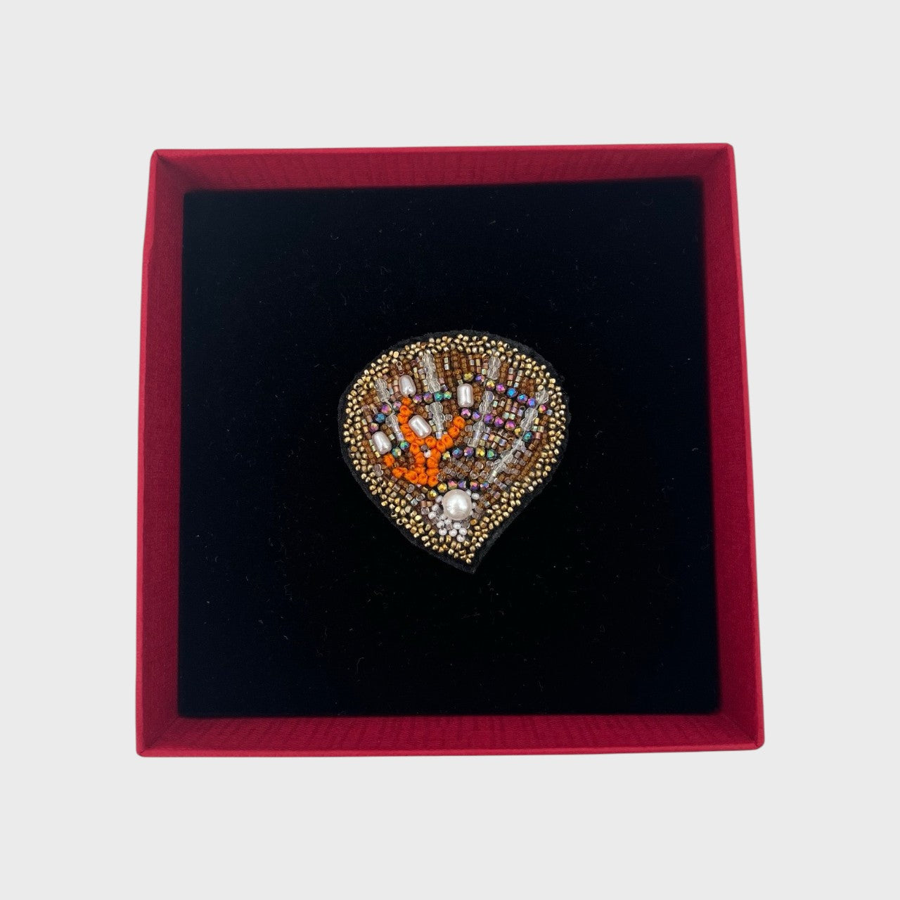 An embroidered brooch representing an oyster in a box. 