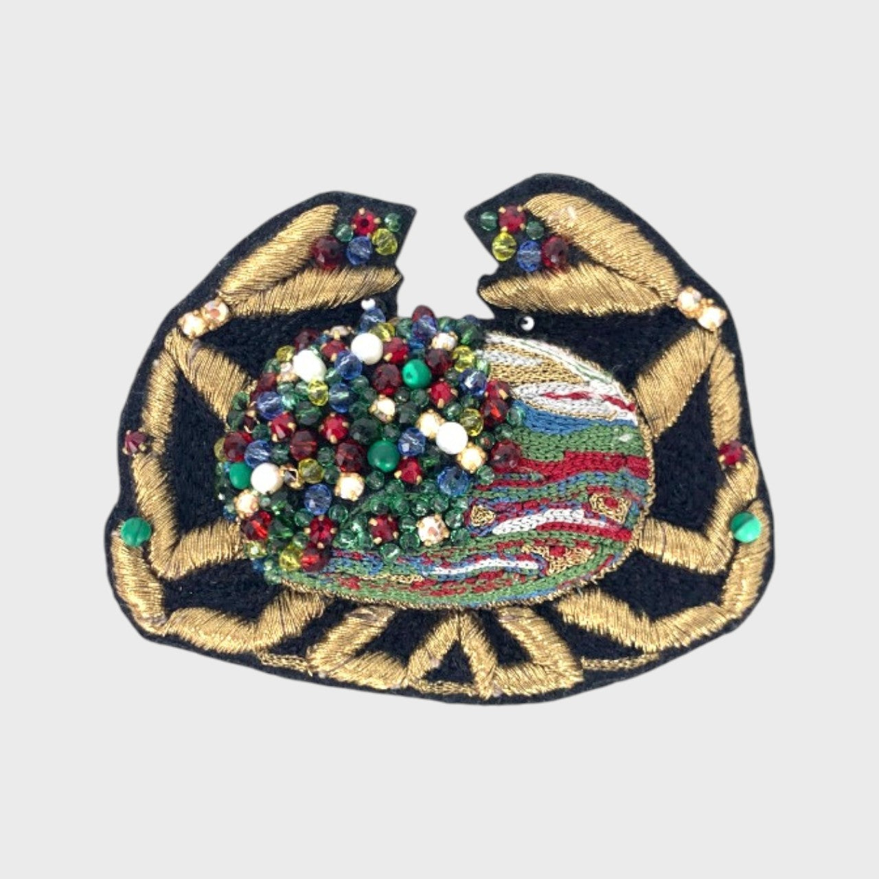 An embroidered brooch representing a crab with black, yellow and  green details. 