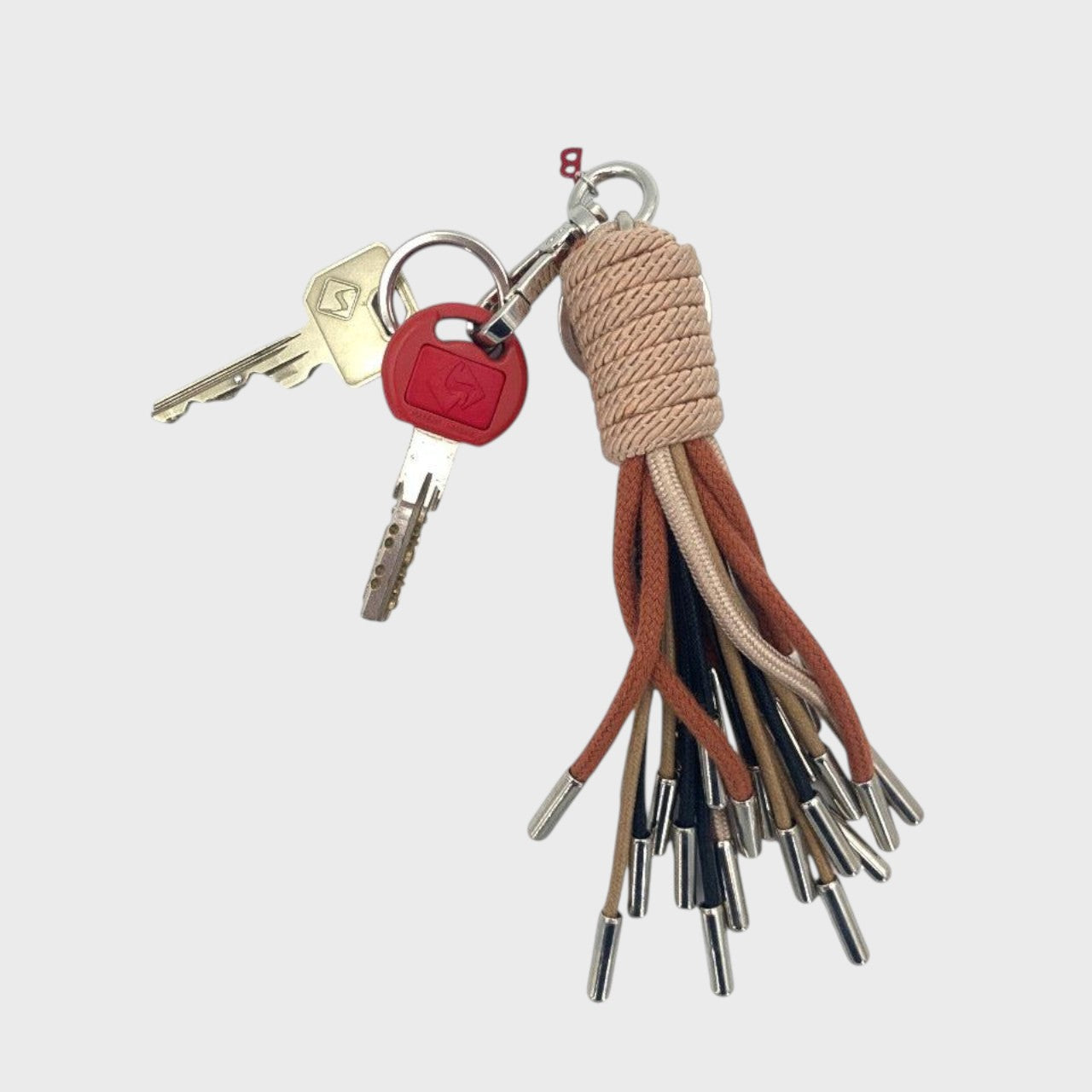 Keychain with keys attached with neutral coloured tassels on a white background